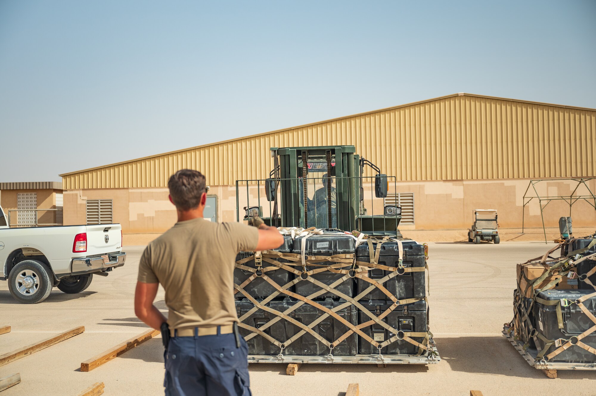U.S. Air Force Airmen from the 379th Air Expeditionary Wing move a pallet of cargo to its shipping lane in preparation for inspection and loading onto a departing flight during exercise Accurate Test 22 at Thumrait Air Base, Oman, May 22, 2022. The Airmen worked together to guide the pallet on the forklift into position to ensure proper balance on the wooden beams in the shipping lane. (U.S. Air Force photo by Staff Sgt. Dana Tourtellotte)