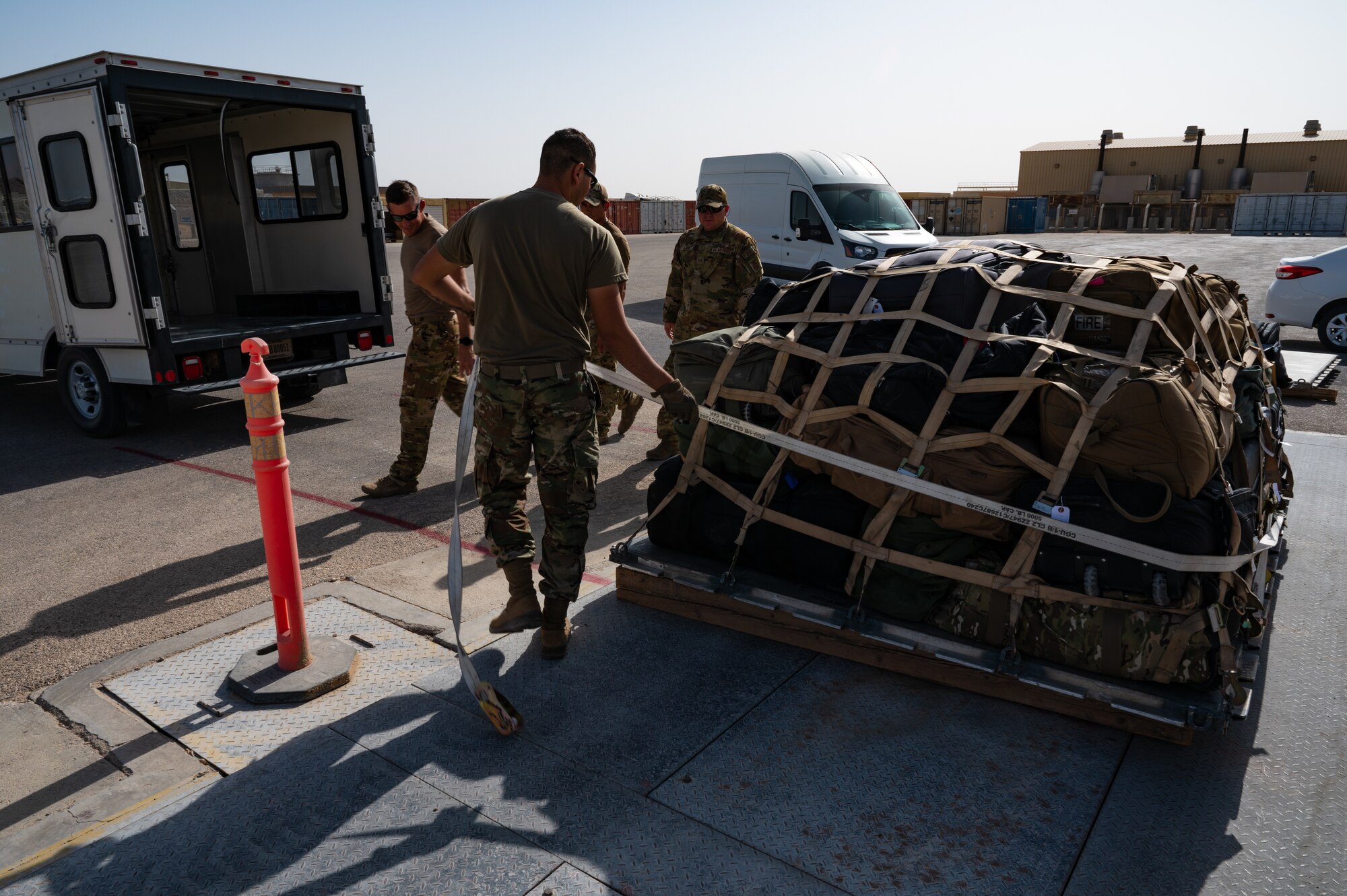 A U.S. Air Force Airman from the 379th Air Expeditionary Wing, net and tie down cargo in preparation for loading it onto a departure flight during exercise Accurate Test 22 at Thumrait Air Base, Oman, May 22, 2022. The Airman used multiple tie downs and rounded up on weight measurements to ensure the load the tie is bearing never exceeded its holding power. (U.S. Air Force photo by Staff Sgt. Dana Tourtellotte)