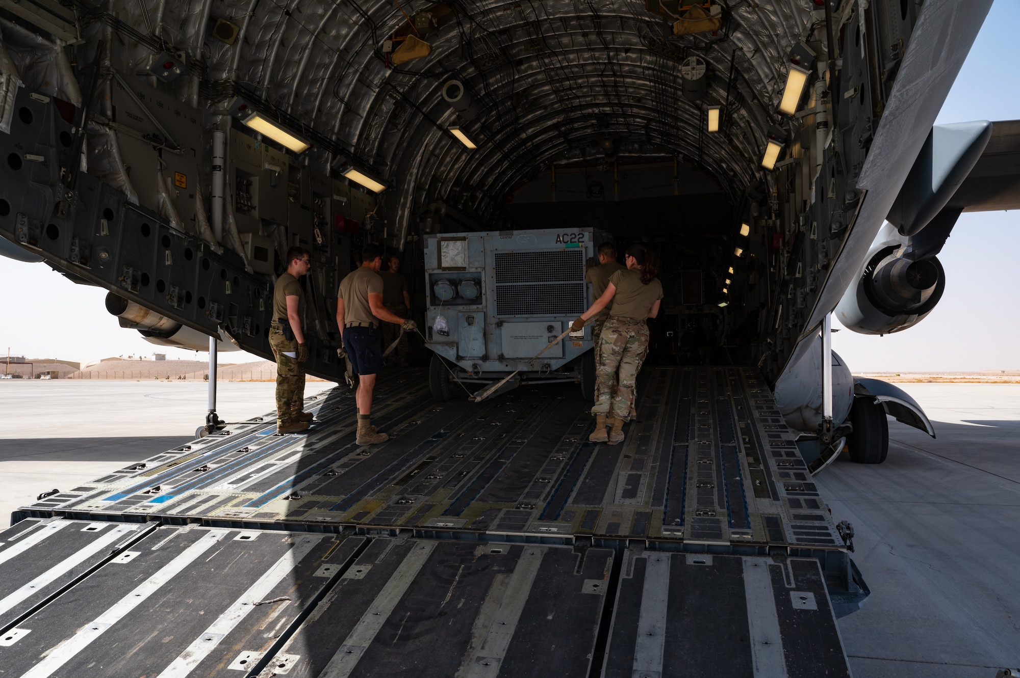 U.S. Air Force Airmen from the 379th Air Expeditionary Wing load a mobile air conditioning unit for a departure flight onto a U.S. Air Force C-17 Globemaster during exercise Accurate Test 22 at Thumrait Air Base, Oman, May 22, 2022.  Loading aircraft is performed systematically, using a computer program to optimize space and weight distribution for each flight and its passengers. (U.S. Air Force photo by Staff Sgt. Dana Tourtellotte)