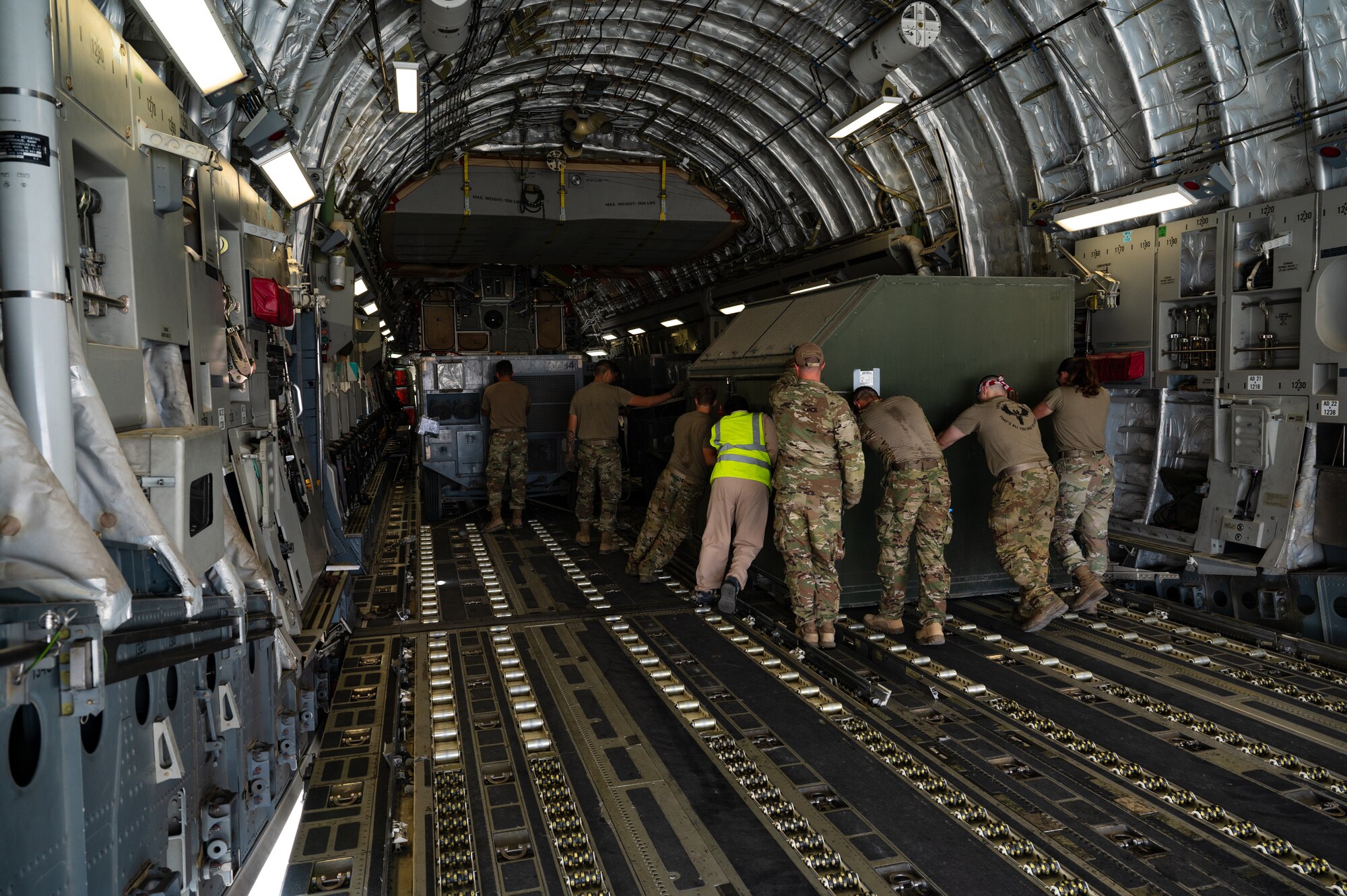 U.S. Air Force Airmen from the 379th Air Expeditionary Wing push cargo into place inside a U.S. Air Force C-17 Globemaster in preparation for a departure flight during exercise Accurate Test 22 at Thumrait Air Base, Oman, May 22, 2022. Small wheels on the aircraft cargo bay floor allow Airmen to push and pull heavy cargo in any direction to optimize placement within the plane. (U.S. Air Force photo by Staff Sgt. Dana Tourtellotte)