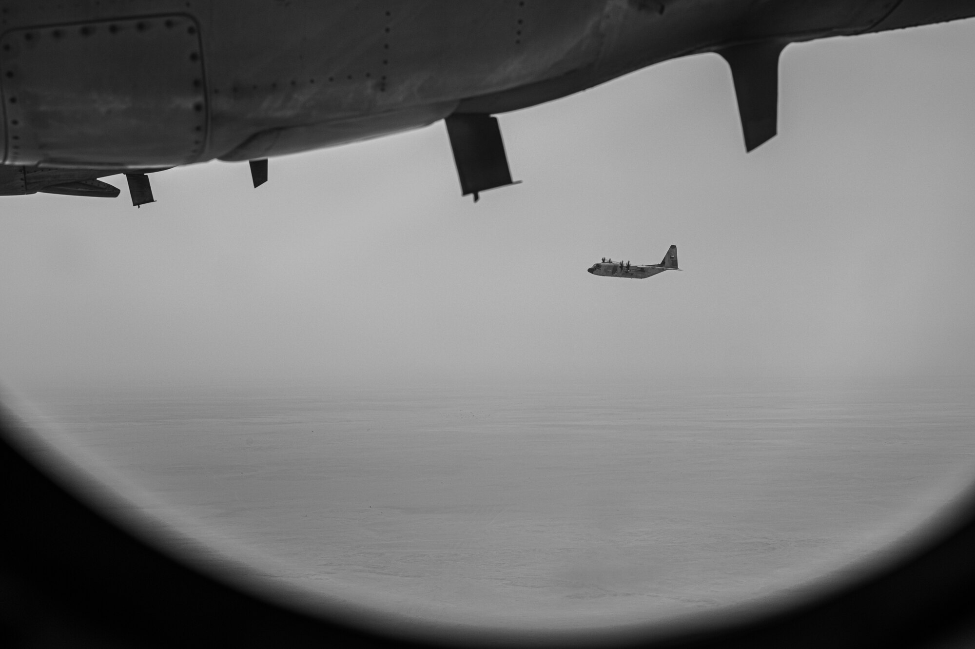 A Royal Air Force of Oman C-130 flies over the desert in Oman, during a combat exercise as part of Accurate Test 22, May 19, 2022. This exercise created opportunities for U.S. aircrew and RAFO Airmen to employ tactical evasive flight maneuvers and a simulated mid-flight payload drop. (U.S. Air Force photo illustration by Staff Sgt. Dana Tourtellotte)