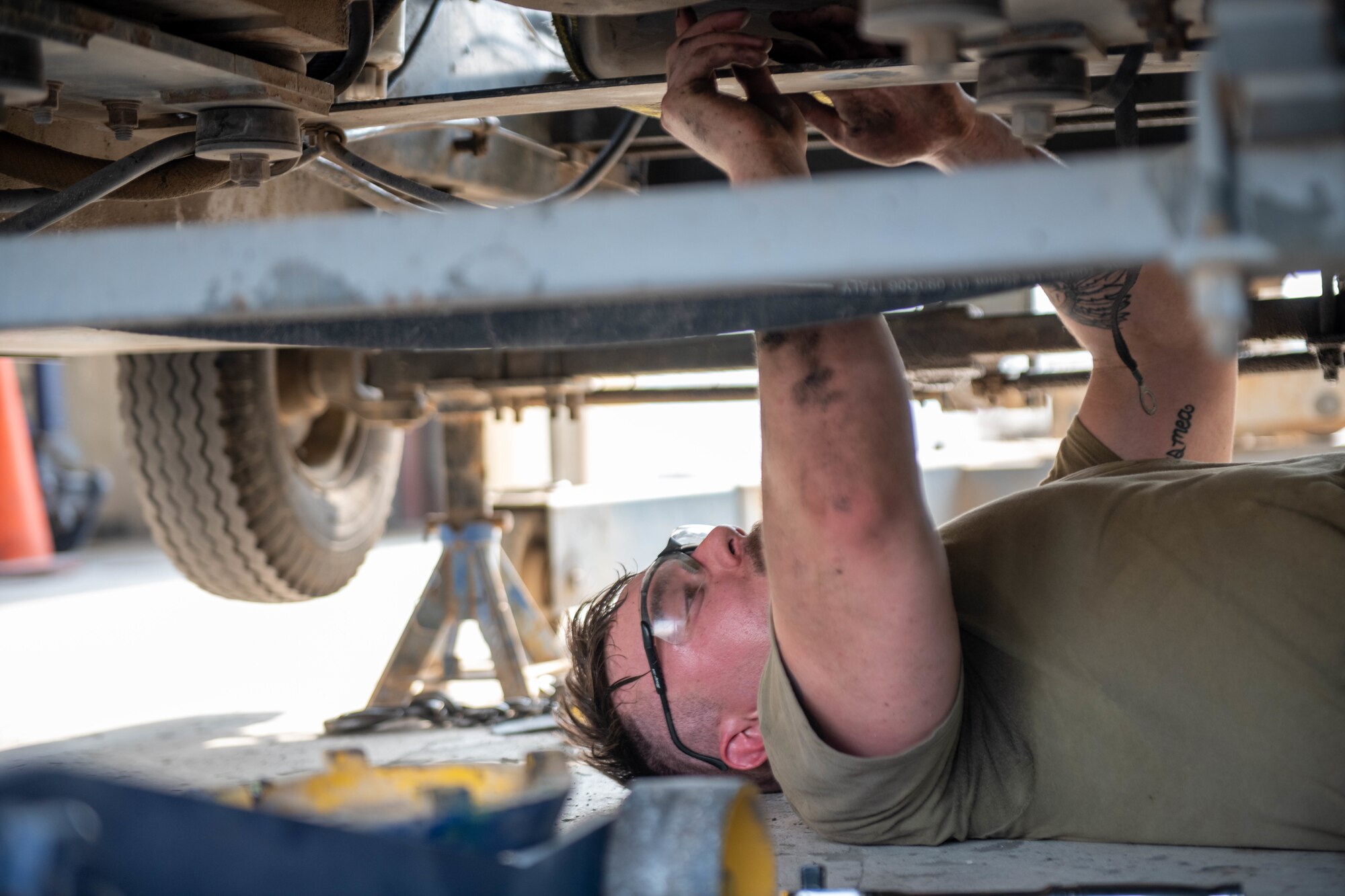 U.S. Air Force Airman 1st Class Cameron Waters, 379th Air Expeditionary Wing Aerospace Ground Equipment Specialist, loosens bolts on the underside of a generator motor on Al Udeid Air Base, Qatar, June 9, 2022. Equipment such as jack stands and tire chalks are used to secure the machinery in place during maintenance. (U.S. Air National Guard photo by Airman 1st Class Constantine Bambakidis)