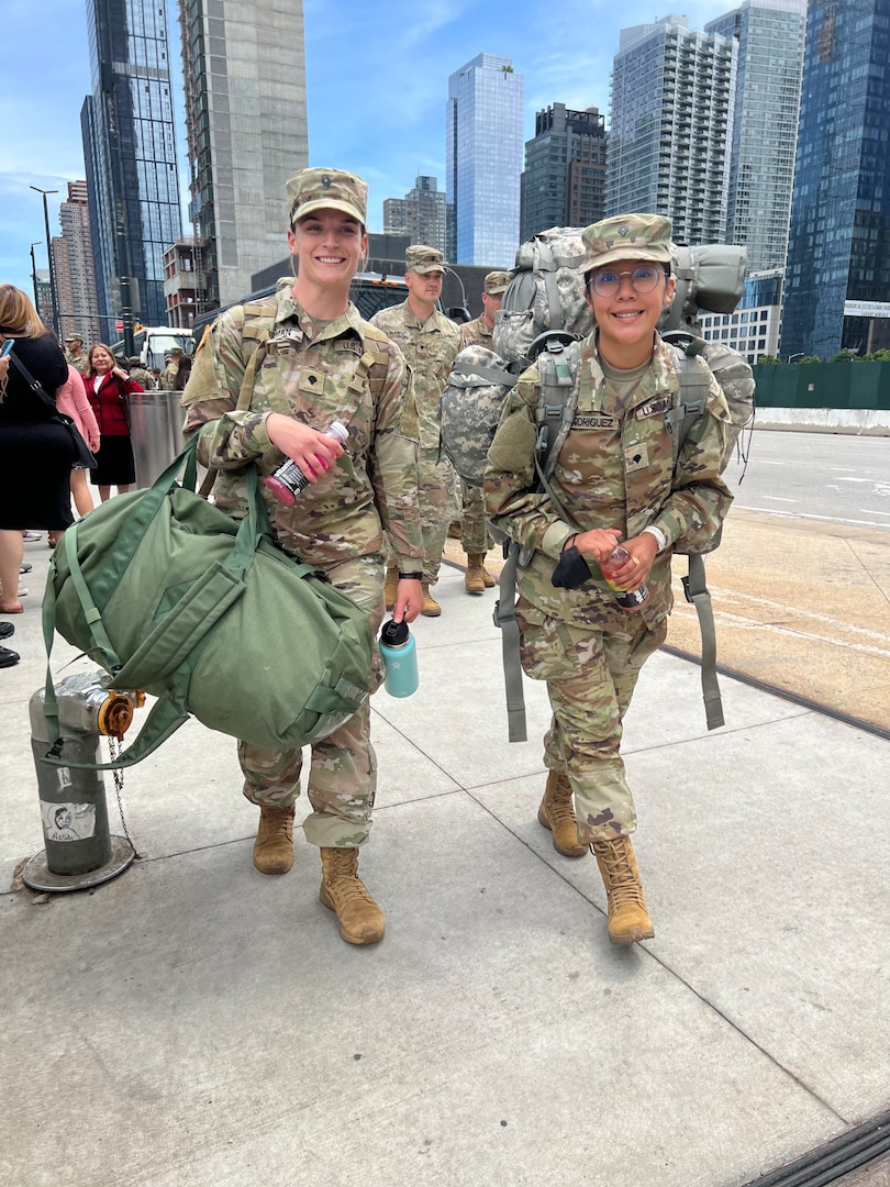 New York Army National Guard Spcs. Lori Gorman and Jahaira Rodriguez, both assigned to Headquarters Company of the 1st Battalion, 69th Infantry, head toward buses taking them to Fort Drum, New York, for training following a farewell event June 14, 2022, at Jacob Javits Convention Center in New York City. The Soldiers will be deploying to the Horn of Africa in September.