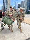 New York Army National Guard Spcs. Lori Gorman and Jahaira Rodriguez, both assigned to Headquarters Company of the 1st Battalion, 69th Infantry, head toward buses taking them to Fort Drum, New York, for training following a farewell event June 14, 2022, at Jacob Javits Convention Center in New York City. The Soldiers will be deploying to the Horn of Africa in September.