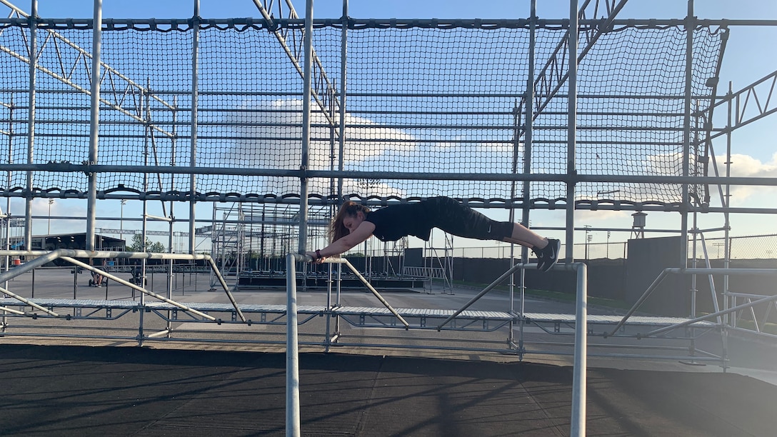 A participant crosses a parallel bar obstacle perpendicularly with her hands on one bar and her feet on the other.