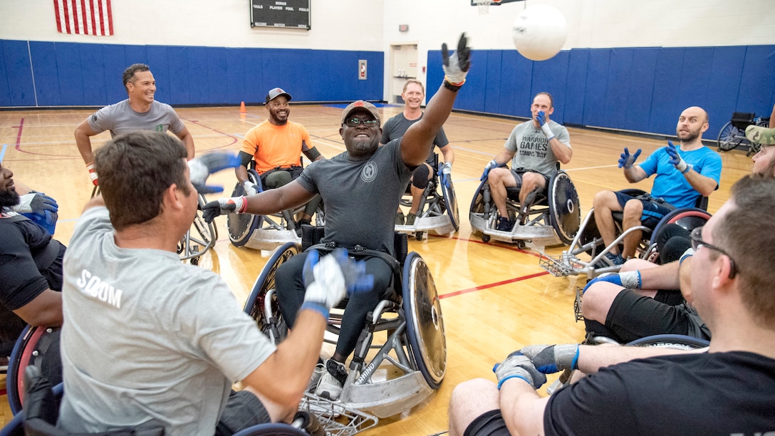 An athlete reaches for a rugby ball in the air during a game of "keep away" at wheelchair rugby practice.