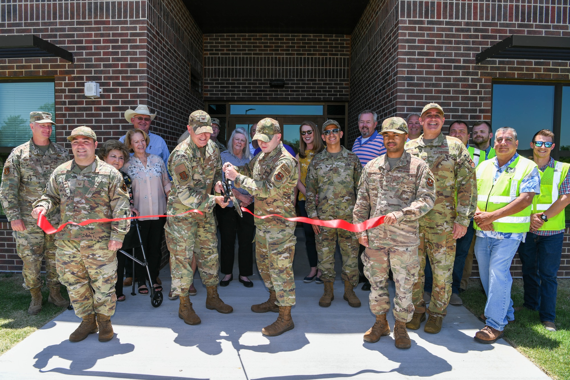 U.S. Air Force Col. Blaine Baker (center left), 97th Air Mobility Wing commander, and Airman Evin Hughes, 97th Communications Squadron network operations technician, cut a ribbon to celebrate the completion of a new dormitory at Altus Air Force Base, Oklahoma, June 13, 2022. The new dorm cost an estimated $24.6 million and will support 116 permanent-party Airmen. (U.S. Air Force photo by Airman 1st Class Trenton Jancze)