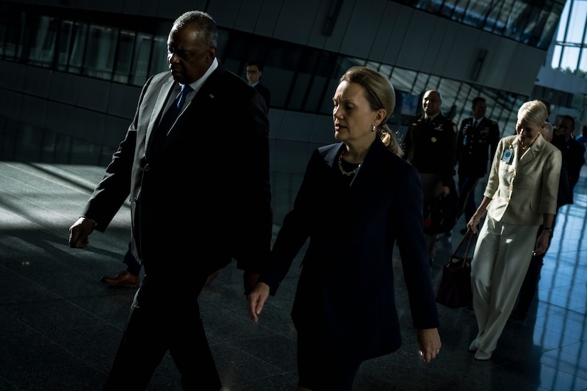 A man and a woman walk together through the lobby of a building.