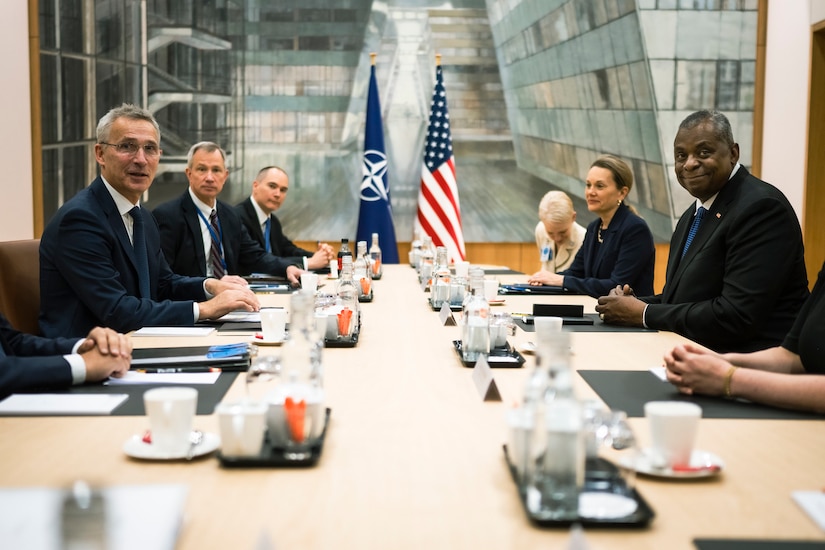 Several people wearing business attire sit at a table during a meeting.