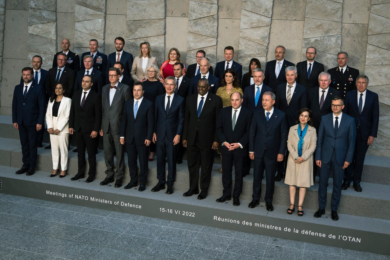 Three rows of people stand on the steps of a building for a group photo.