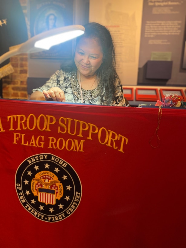 woman embroiders flag