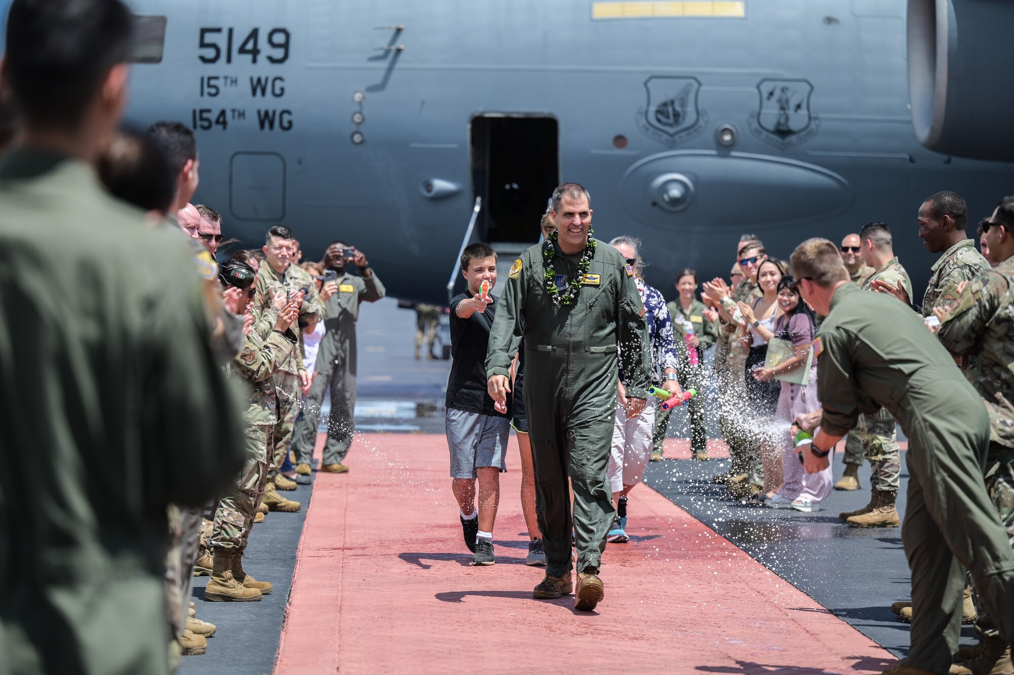 Col. Daniel Dobbels, 15th Wing commander, and his family walk through a ceremonial gauntlet on Hickam Field at Joint Base Pearl Harbor-Hickam, Hawaii, June 15, 2022. Dobbels plans to retire from the Air Force after 24 years of service. (U.S. Air Force photo by Staff Sgt. Alan Ricker)