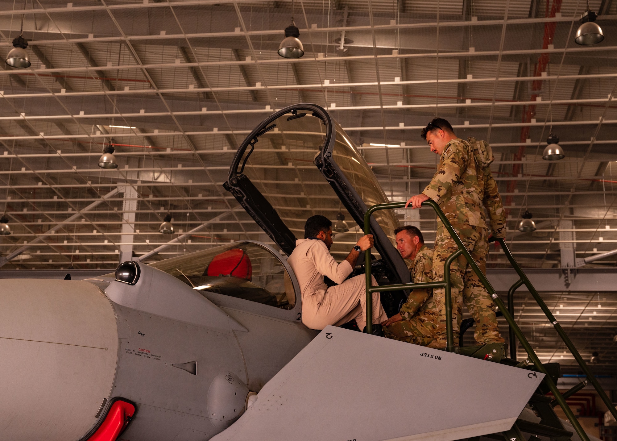 A Royal Air Force of Oman fire chief, left, briefs U.S. Air Force firefighters from the 379th Air Expeditionary Wing, on RAFO fire safety measures in a RAFO Eurofighter Typhoon aircraft at Thumrait Air Base, Oman, May 18, 2022. The RAFO fire chief showed the U.S. Airmen the fire safety measures that reside within the cockpit. (U.S. Air Force photo by Staff Sgt. Dana Tourtellotte)