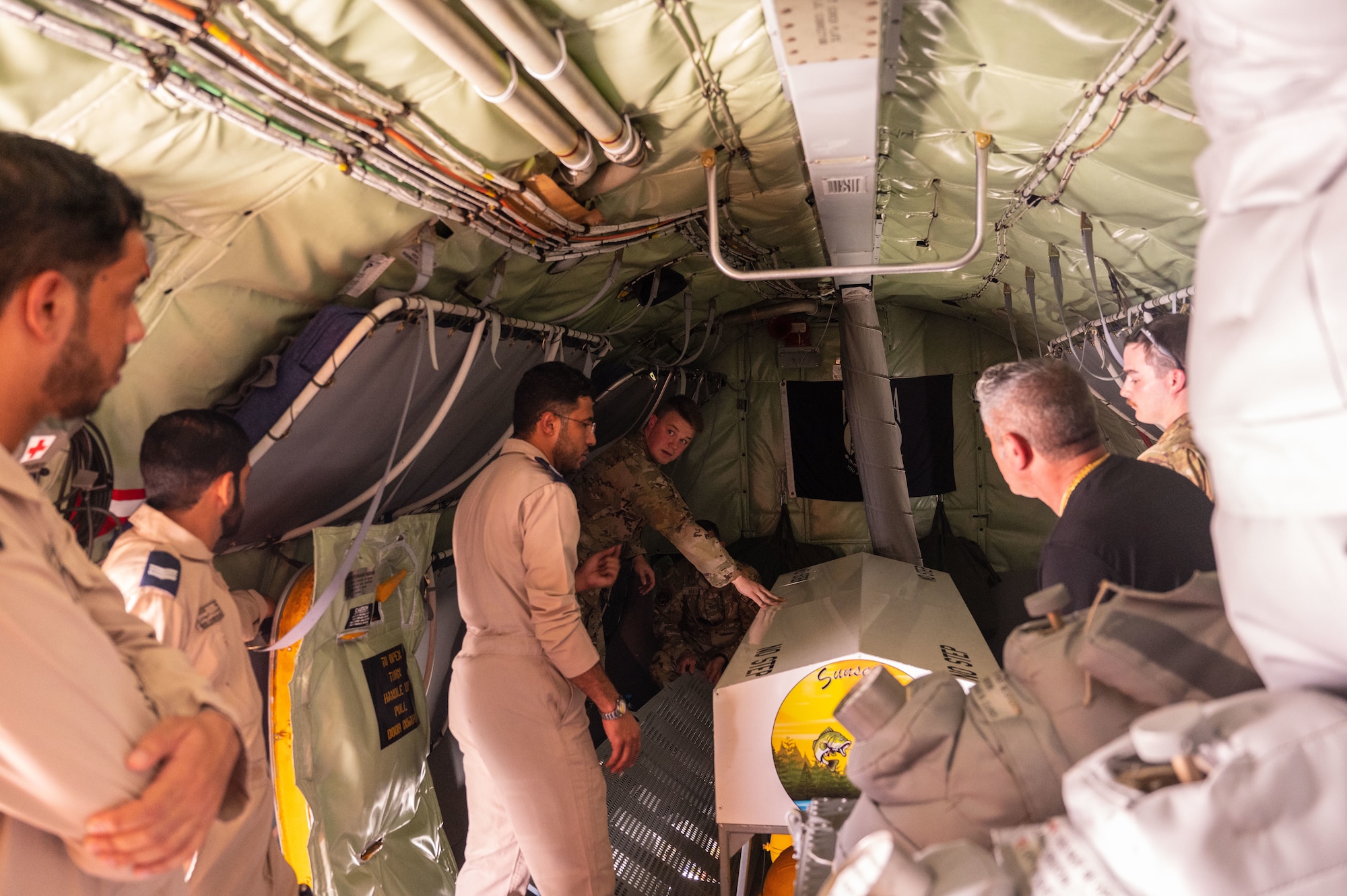 U.S. Air Force Staff Sgt. Nathaniel Dressler, a firefighter assigned to the 379th Air Expeditionary Wing, demonstrates aircraft safety features on a U.S. Air Force KC-135 Stratotanker aircraft, assigned to the 340th Expeditionary Air Refueling Squadron, to Royal Air Force of Oman firemen at Thumrait Air Base, Oman, May 18, 2022. Dressler shared details about operating the KC-135 aircraft’s fire suppression and evacuation systems throughout the interior of the aircraft. (U.S. Air Force photo by Staff Sgt. Dana Tourtellotte)