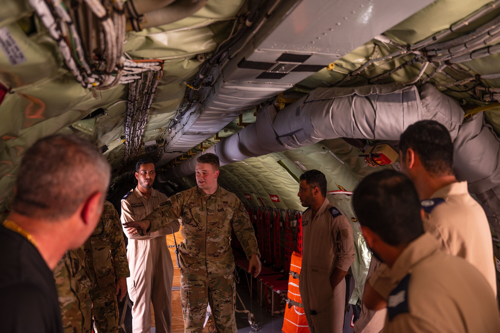 U.S. Air Force Staff Sgt. Nathaniel Dressler, center, a firefighter assigned to the 379th Air Expeditionary Wing, briefs Airmen of the Royal Air Force of Oman on aircraft fire safety while aboard a U.S. Air Force KC-135 Stratotanker aircraft, assigned to the 340th Expeditionary Air Refueling Squadron, at Thumrait Air Base, Oman, May 18, 2022. Dressler shared details about operating the KC-135 aircraft’s fire suppression and evacuation systems. (U.S. Air Force photo by Staff Sgt. Dana Tourtellotte)