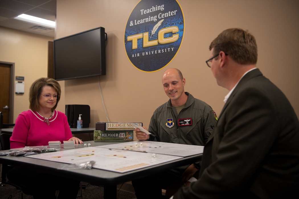 Dr. Ruth Busby, Air University Teaching and Learning Center instructor, Lt. Col. Joseph Bisson, Profession of Arms Center of Excellence instructor, and John Hansen, Air University library supervisor, play a strategy board game at Maxwell Air Force Base, Alabama, June 1, 2022. Air University library and the TLC have combined their efforts to bring gamification into the military teaching environment at Air University.