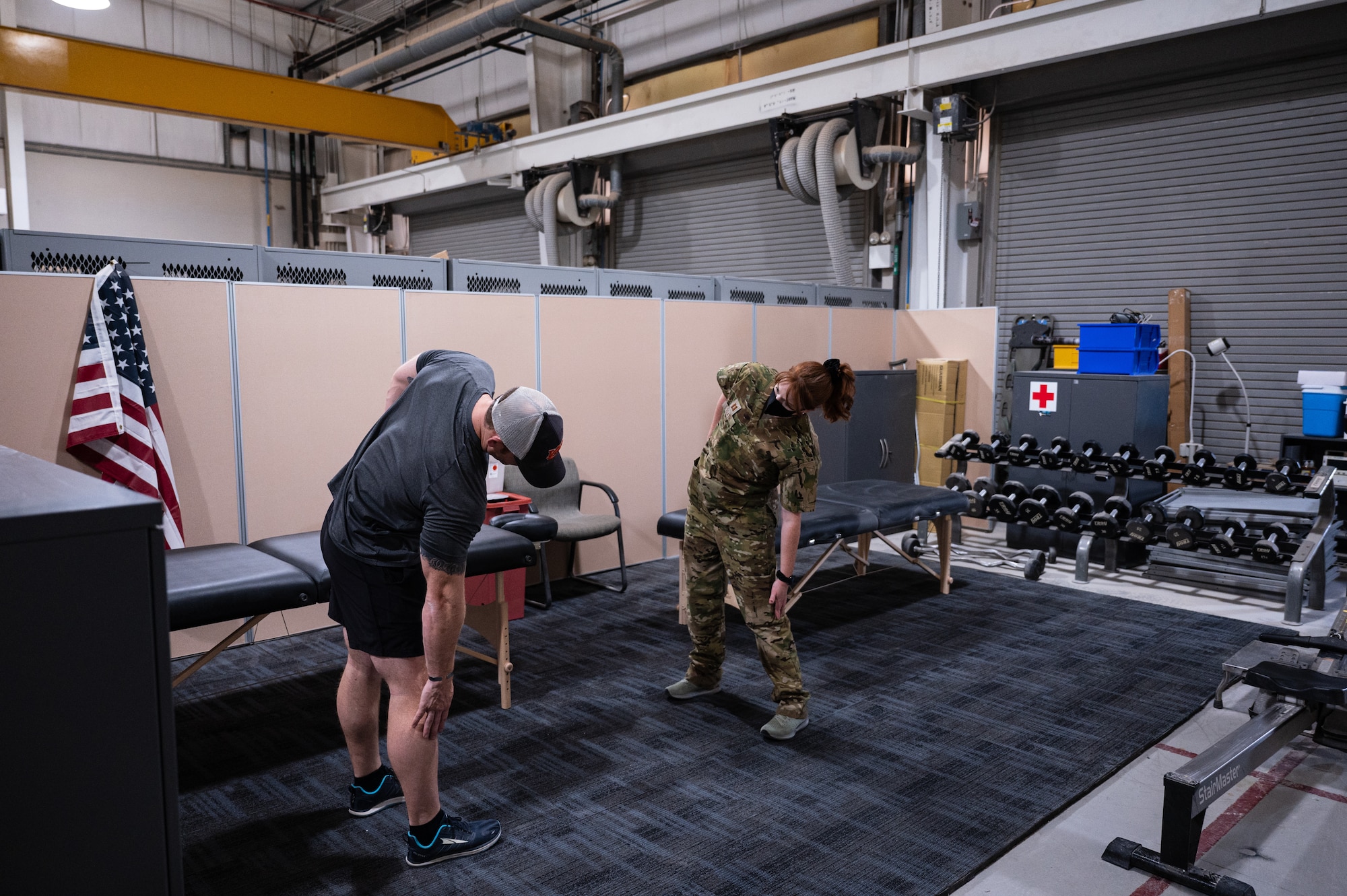 U.S. Air Force Captain Kara Heath, a physical therapist from the 379th Expeditionary Operational Medical Readiness Squadron, Al Udeid Air Base, Qatar, demonstrates to her physical therapy patient how to perform stretch June 10, 2022. Her care helped ensure that an Airman was able to continue to perform his duties without furthering his injuries. (U.S. Air Force photo by Staff Sgt. Dana Tourtellotte)