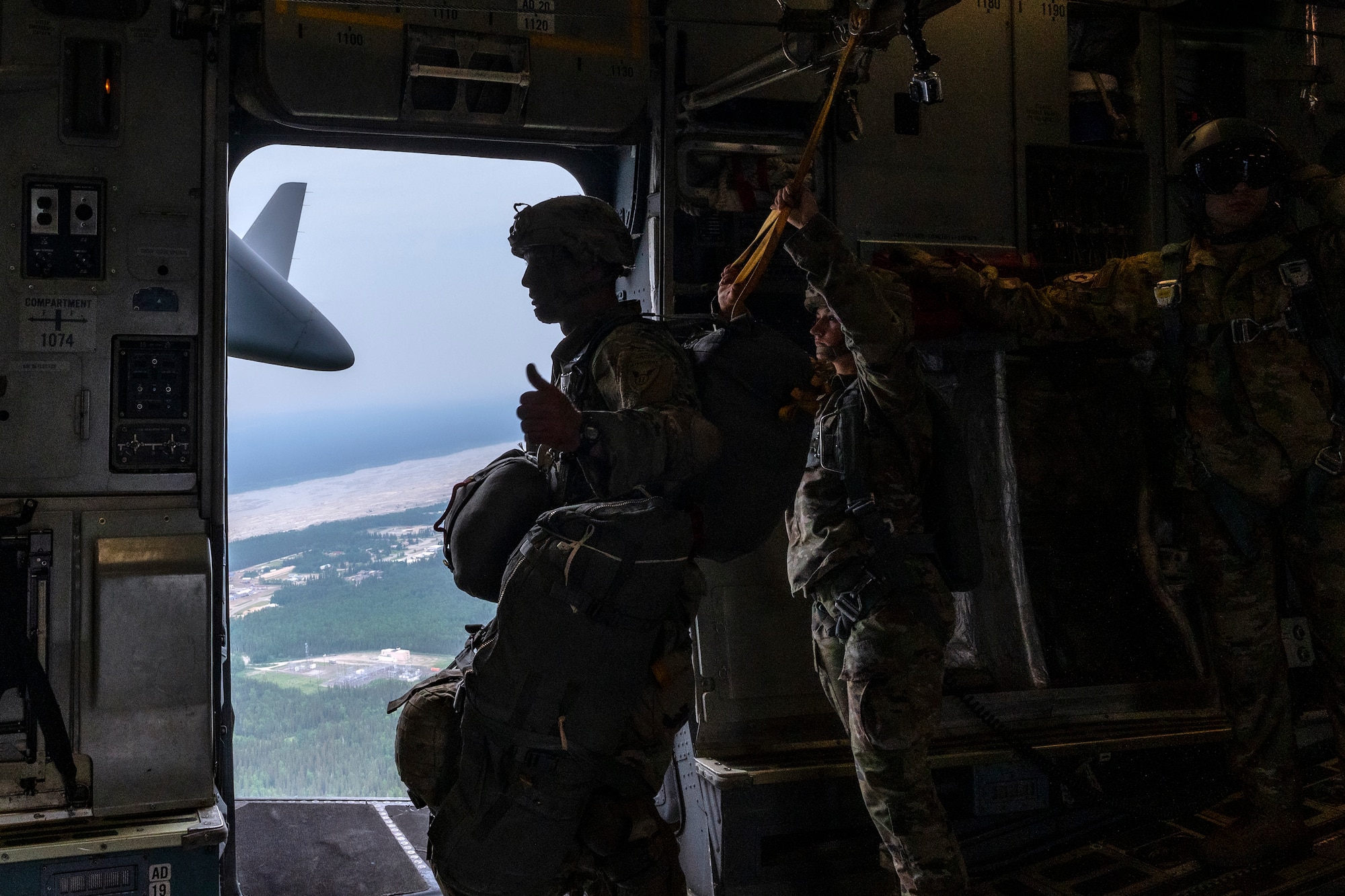 U.S. Army Sgt. 1st Class Charlie Arrendale, gives a thumbs-up signal prior to the paratroopers jumping out of a C-17 Globemaster III from the 517th Airlift Squadron, Joint Base Elmendorf-Richardson, Alaska over Allen Army Airfield, Fort Greely, June 15, 2022. RF-A provides realistic combat training by integrating joint, coalition and multilateral forces into simulated forward operating bases. The paratroopers and Arrendale are assigned to the 2nd Infantry Brigade Combat Team (Airborne), 11th Airborne Division. (U.S. Air Force photo by Sheila deVera)