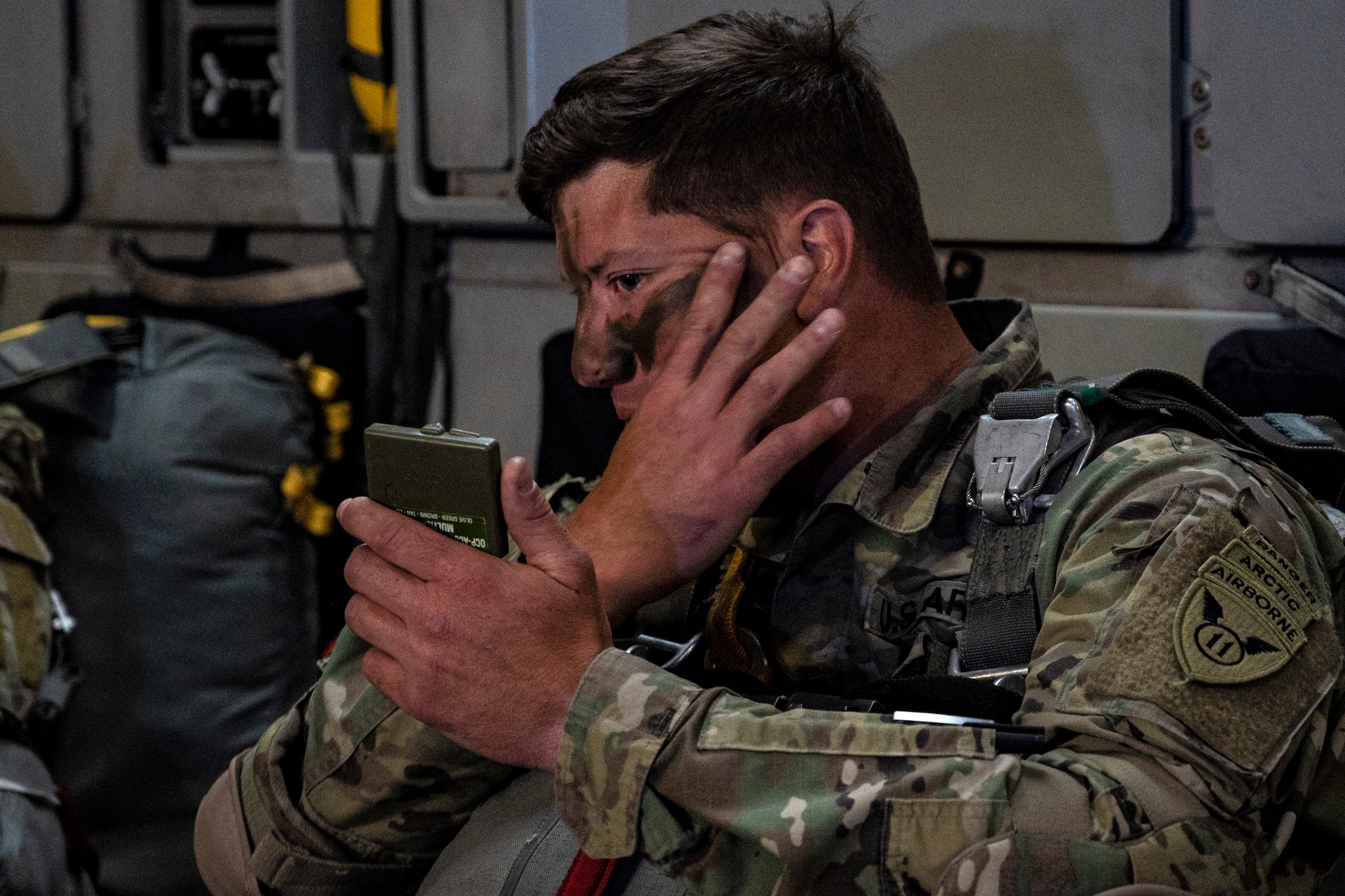 U.S. Army Sgt. 1st Class Charlie Arrendale applies camouflage face paint before jumping out of a C-17 Globemaster III from the 517th Airlift Squadron, Joint Base Elmendorf-Richardson, Alaska during RED FLAG-Alaska 22-2 on June 15, 2022. RF-A provides realistic combat training by integrating joint, coalition and multilateral forces into simulated forward operating bases. Arrendale is assigned to the 3rd Battalion, 509th Infantry Regiment, 2nd Infantry Brigade Combat Team (Airborne), 11th Airborne Division. (U.S. Air Force photo by Sheila deVera)
