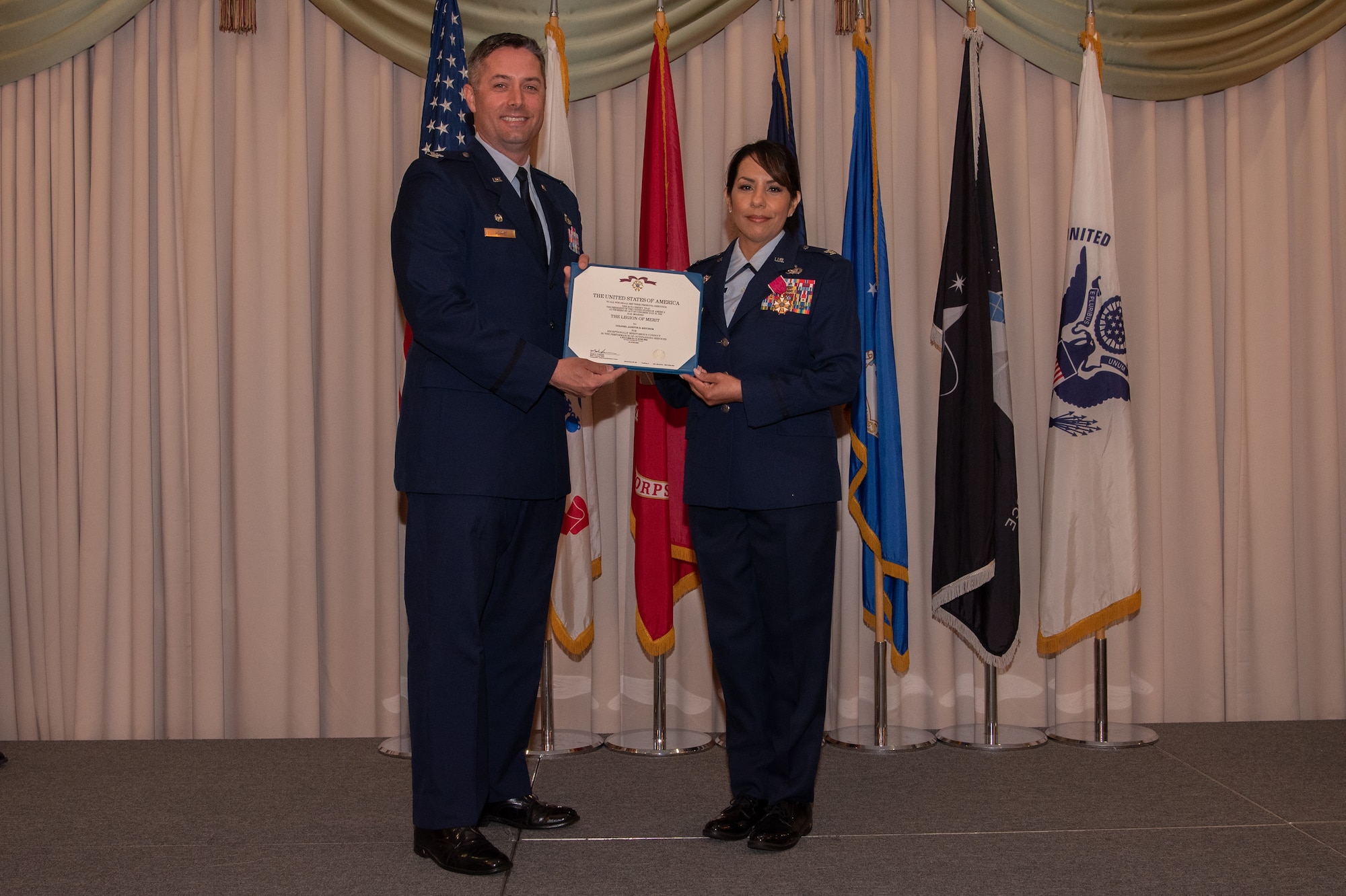 U.S. Air Force Col. Janette Ketchum is presented with the Legion of Merit by U.S. Air Force Col. Wes Adams.