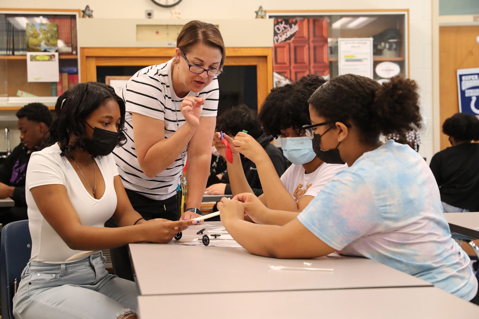 A science teacher Erin Lewis explains instructions for a STEM activity with her students as they work as a team to build a balloon buggy.