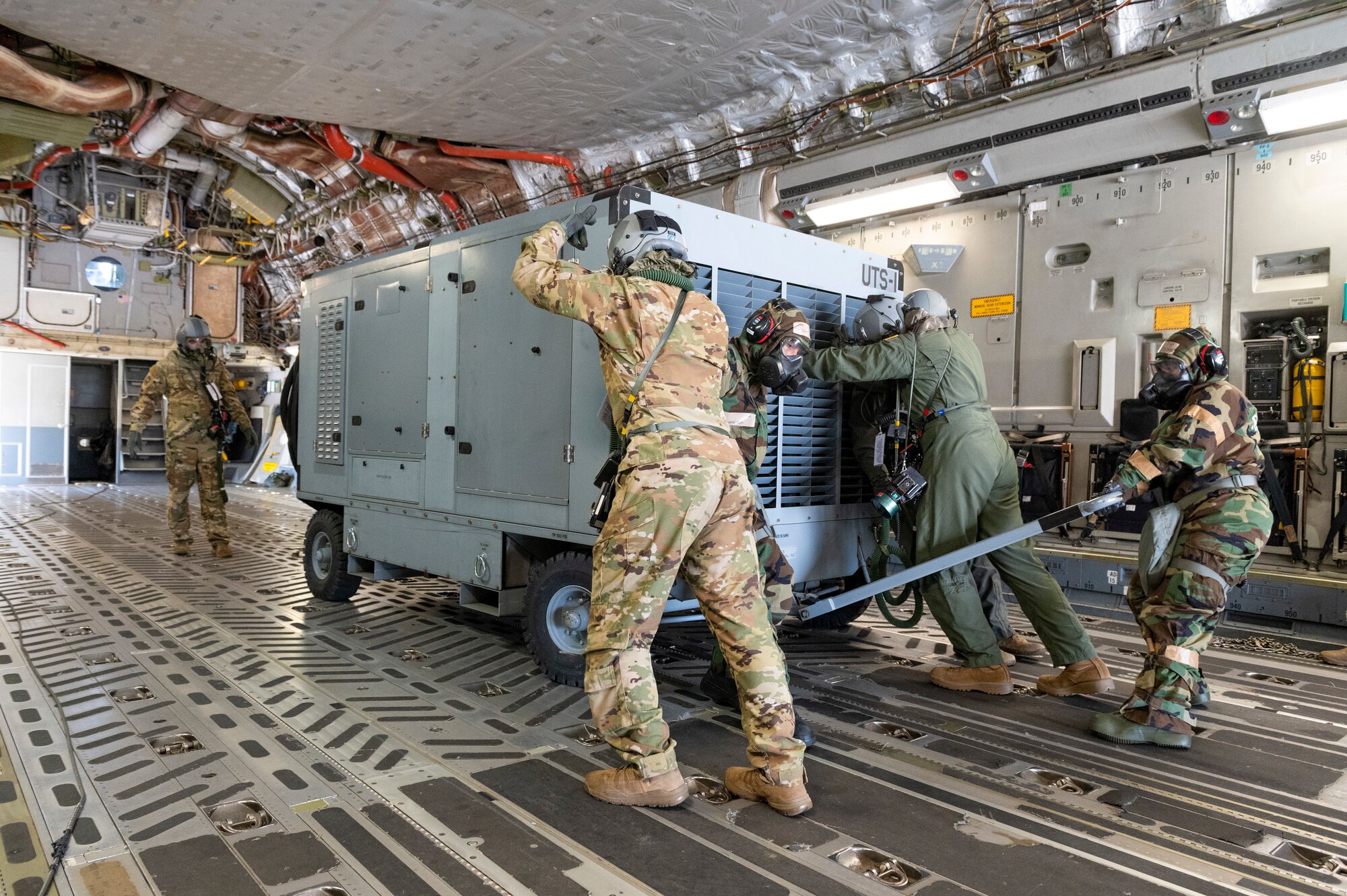 Loadmasters and air transportation specialists with the 167th Airlift Wing, load a hydraulic test stand onto a C-17 Globemaster III aircraft during a simulated chemical environment training at the 167th Airlift Wing, Martinsburg, West Virginia, June 10, 2022. This training included maintainers, loadmasters, pilots and other personnel to simulate the process of preparing, loading and flying the aircraft while in a hazardous chemical environment.