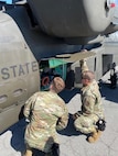 Two mechanics work on an Apache Helicopter