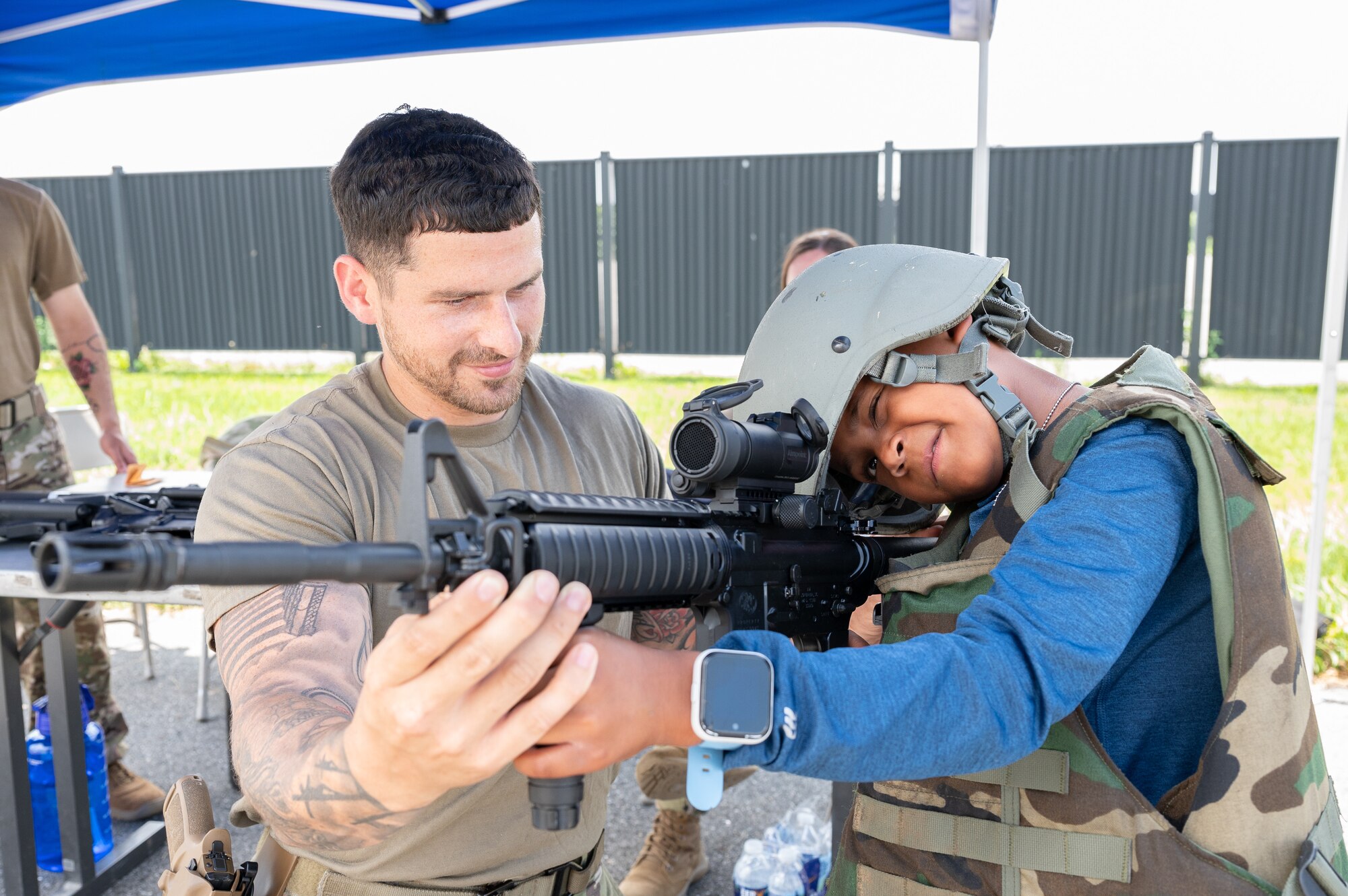 Staff Sgt. Ryan Dearborn, 436th Security Forces Squadron combat arms instructor, shows Zaire Thomas how to aim an M4-A1 carbine during the 2022 Children’s Day Celebration at Dover Air Force Base, Delaware, June 13, 2022. This year’s celebration offered outdoor activities and a mock deployment line to Team Dover families. (U.S. Air Force photo by Mauricio Campino)