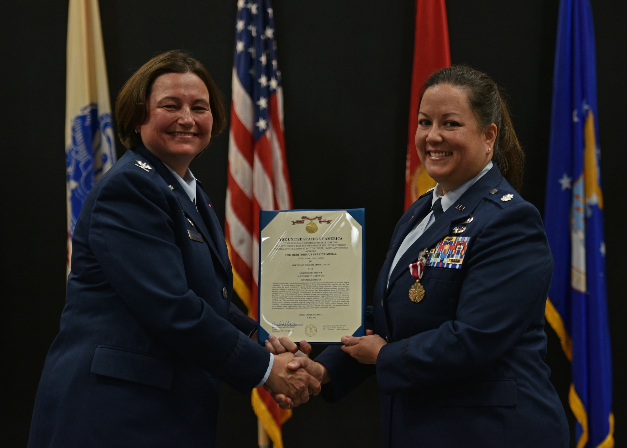 U.S. Air Force Col. Angelina Maguinness, 17th Training Group commander, presents a decoration to Lt. Col. Linda Davis, outgoing 17th Training Support Squadron commander, during the 17th TRSS change of command at the Powell Event Center, Goodfellow Air Force Base, Texas, June 17, 2022. Davis was highlighted for her outstanding leadership of the 17th TRSS during her two years in command. (U.S. Air Force photo by Senior Airman Ashley Thrash)