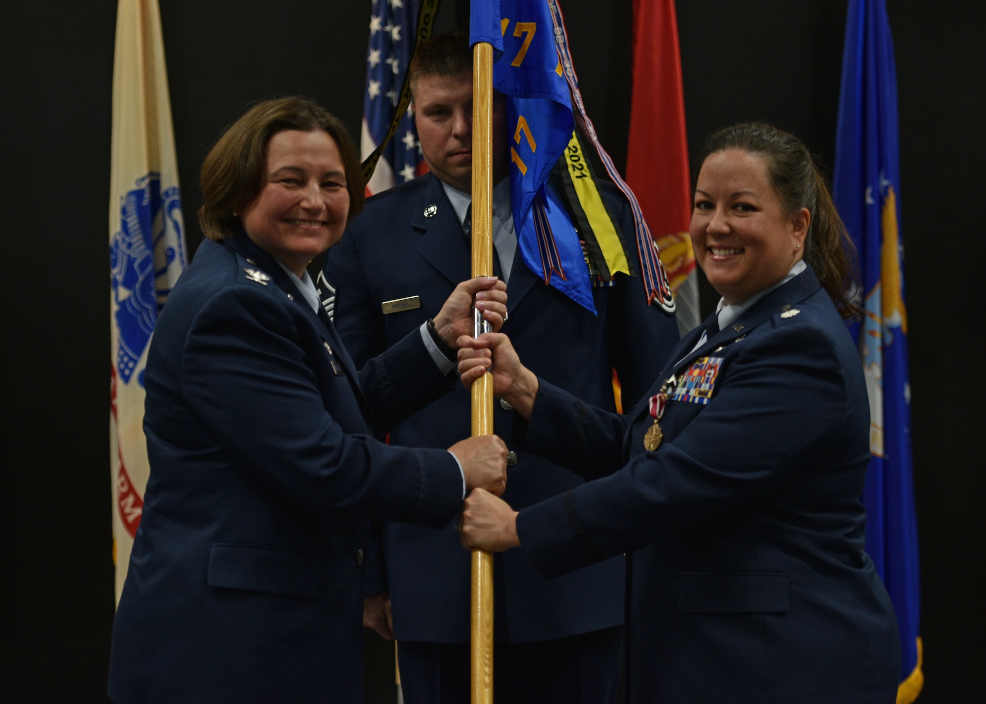 U.S. Air Force Lt. Col. Linda Davis, right, 17th Training Support Squadron outgoing commander, relinquishes command to Col. Angelina Maguinness, 17th Training Group commander, during the 17th TRSS change of command ceremony at the Powell Event Center, Goodfellow Air Force Base, Texas, June 17, 2022. Passing the guidon physically represents the symbolism of passing the squadron responsibilities to the next commander. (U.S. Air Force photo by Senior Airman Ashley Thrash)
