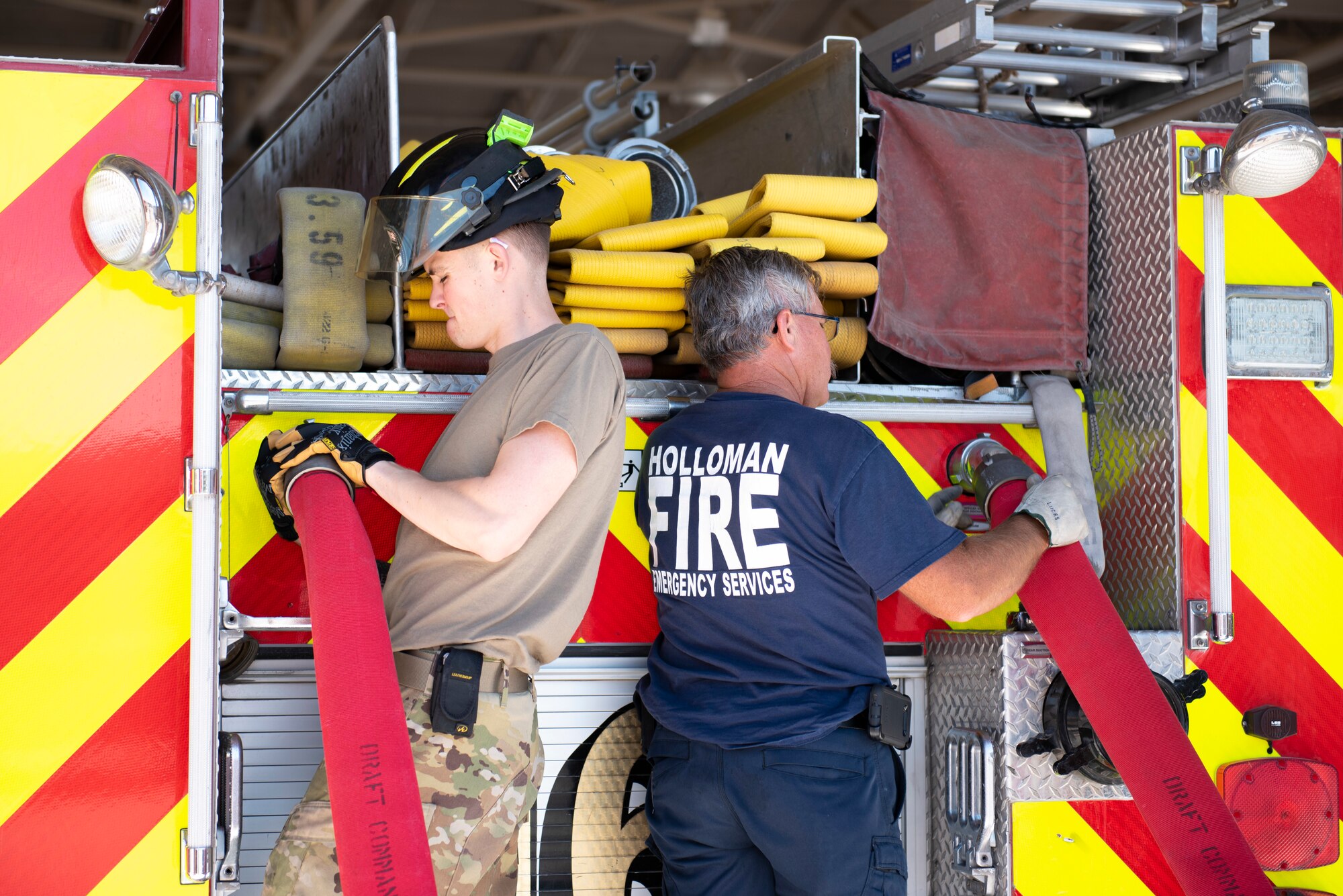 Airman Aiden Quirk, 49th Civil Engineer Squadron, firefighter (left) and Michael Lucas, 49th CES lead firefighter, loosen discharge lines, June 15, 2022, on Holloman Air Force Base, New Mexico.