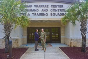 photo USAF Airmen and Civilan stand in front of the 505th Command and Control Wing building.