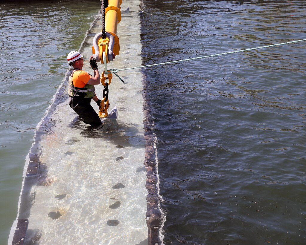 Matt Hansen wades on a submerged stoplog to attach a crane so it can be removed. This is the second of seven stoplogs U.S. Army Corps of Engineers maintenance personnel removed today while opening the MacArthur lock after season maintenance and an extended repair. (U.S. Army Corps of Engineers photo by Bill Dowell)