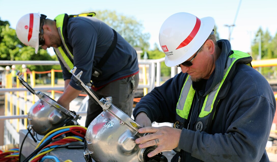 Tyler Ross, right, and Matt Proulx, prepare their diving equipment to remove stoplogs and open the MacArthur Lock today. Divers must go into the water and attach a crane to the stoplogs to remove them. The MacArthur Lock opened today after seasonal maintenance and an extended repair. (U.S. Army Corps of Engineers photo by Bill Dowell)