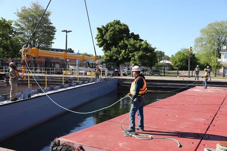 U.S. Army Corps of Engineers maintenance personnel attach a crane to the first stoplog holding back water for the MacArthur Lock. The Corps of Engineers removed the stoplogs and opened the MacArthur Lock today after seasonal maintenance and an extended repair. (U.S. Army Corps of Engineers photo by Bill Dowell)