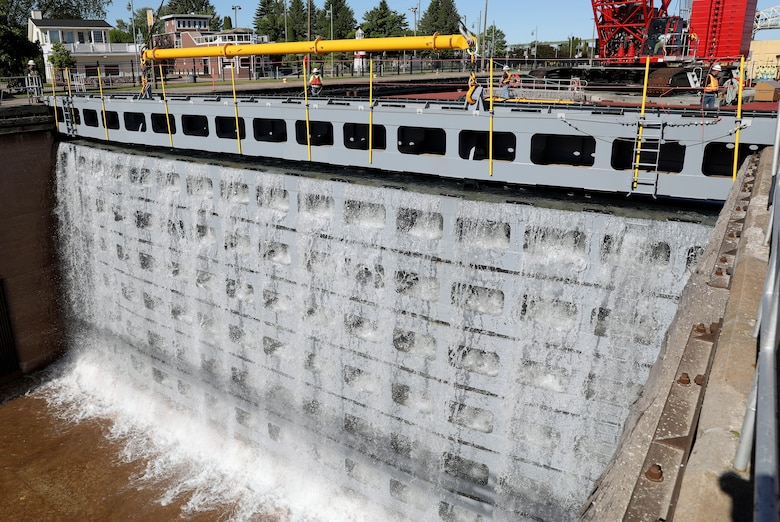 Water begins flowing into MacArthur Lock as a U.S. Army Corps of Engineers crane removes the first stoplog. The Corps of Engineers removed the stoplogs and opened the MacArthur Lock today after seasonal maintenance and an extended repair. (U.S. Army Corps of Engineers photo by Bill Dowell)