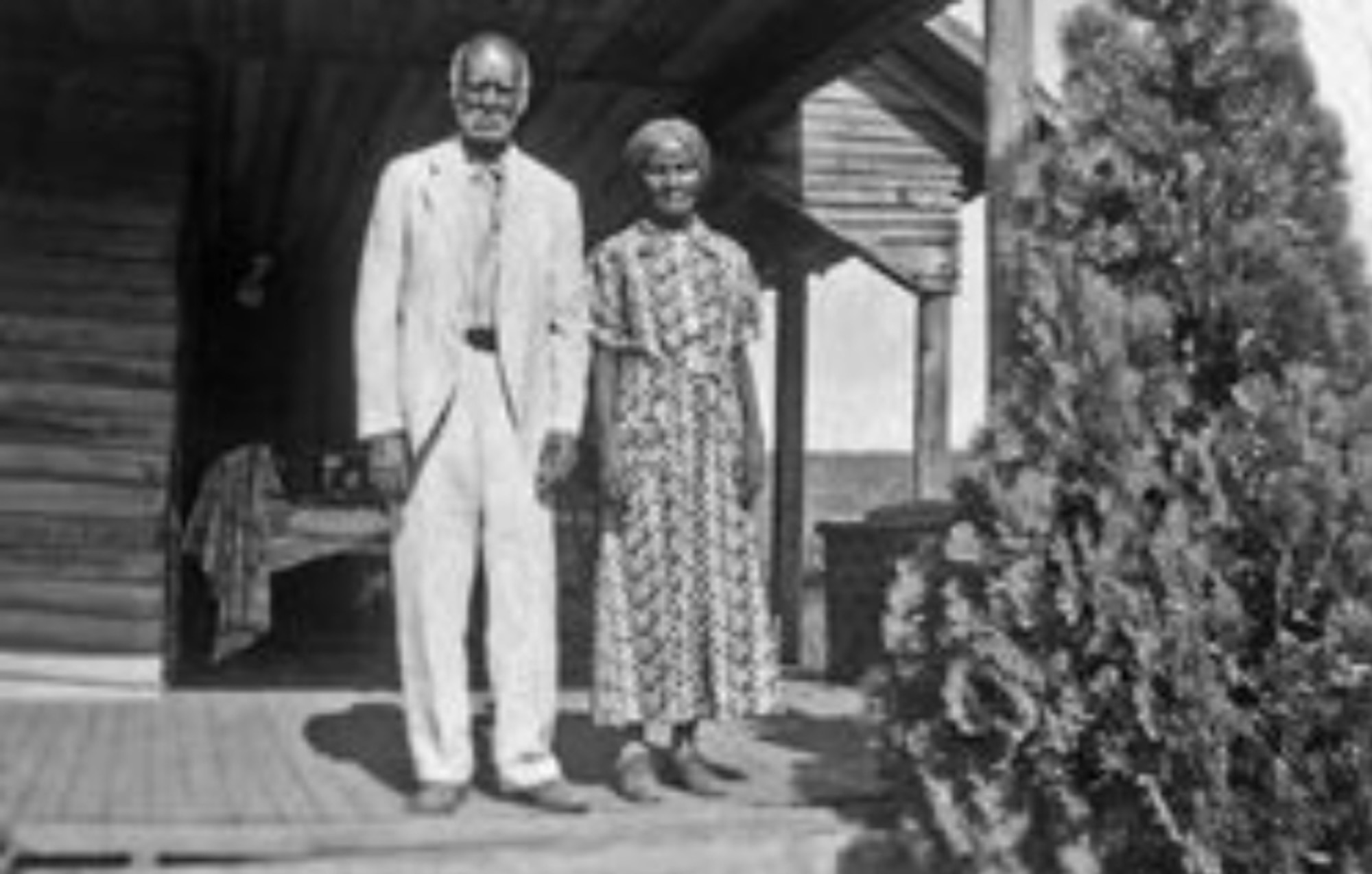 a man and woman stand on a porch in the 1800s