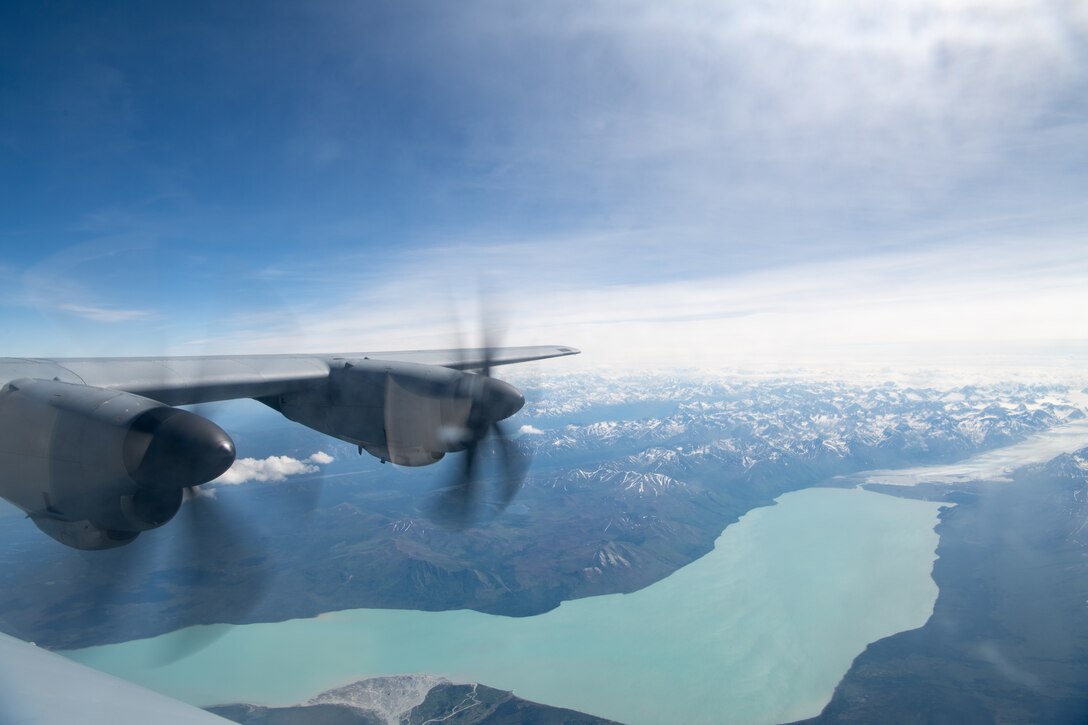 A C-130 flies over an Alaska mountain range.