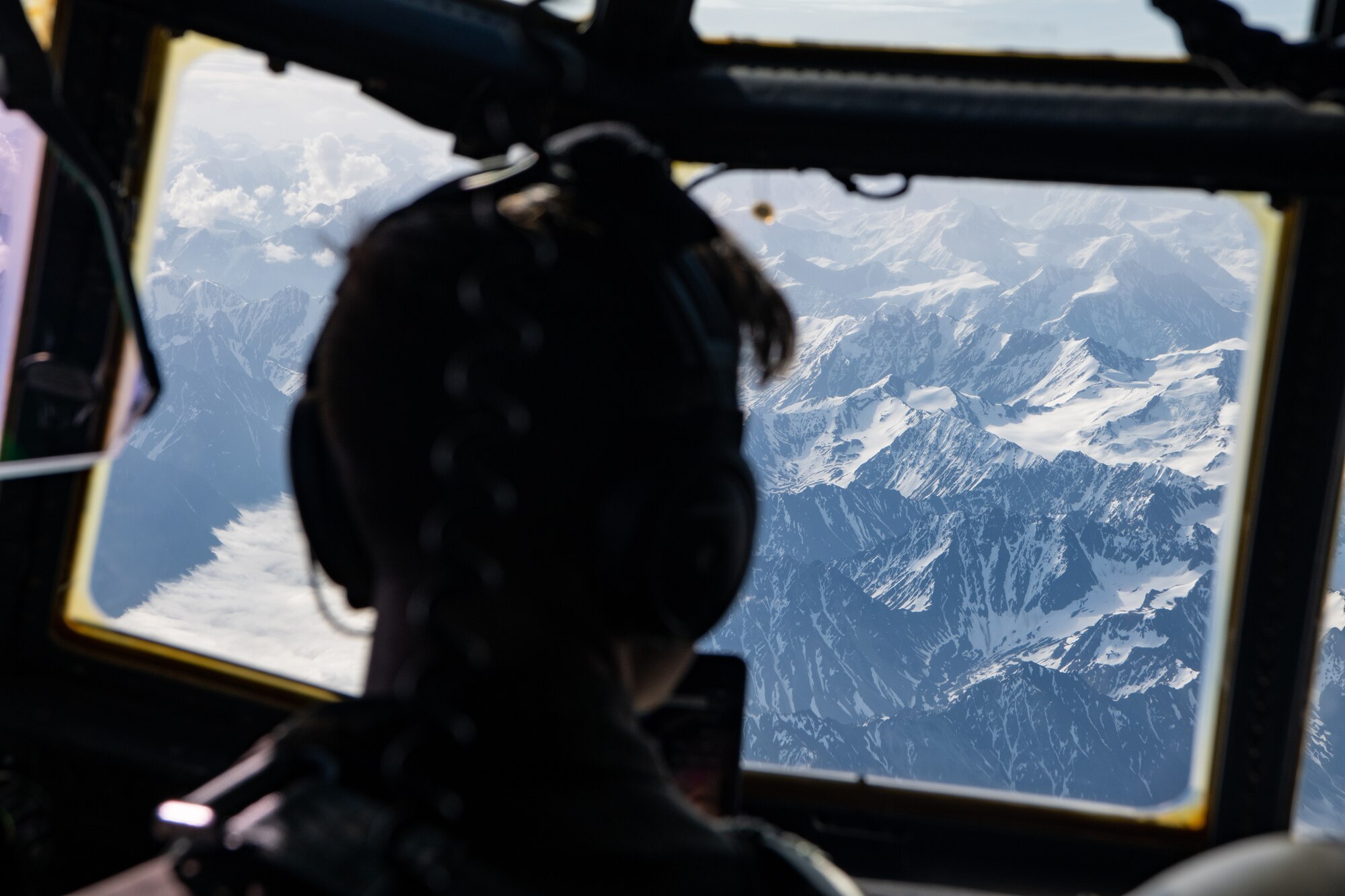 A pilot observes mountains passing below.