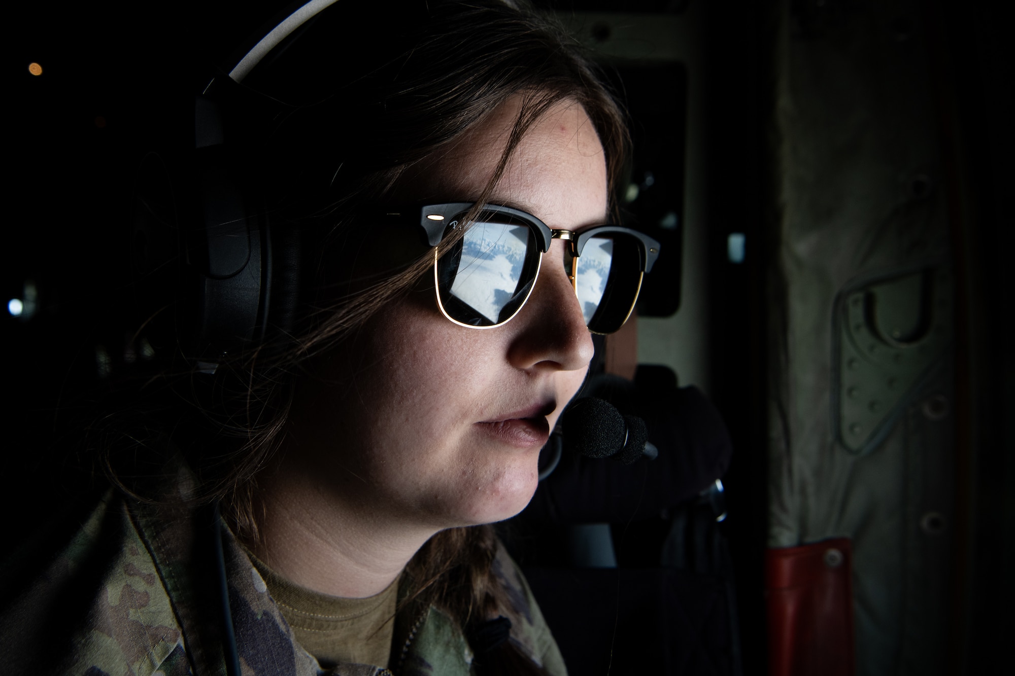 An Airmen looks out of a window on a C-130.