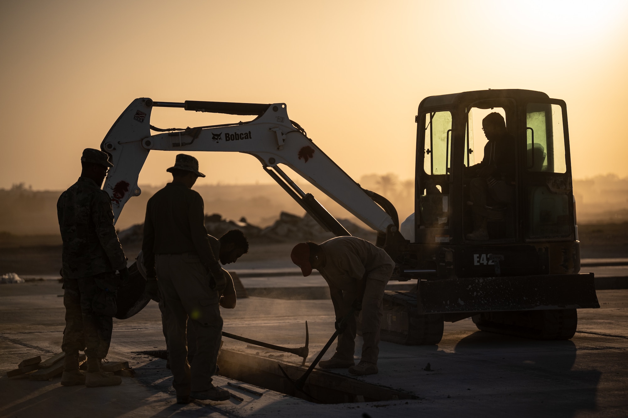 1st Expeditionary Civil Engineer Group Airmen remove wood forms used for airfield lighting placement during a runway overrun repair project at an undisclosed location in Southwest Asia, June 8, 2022. The runway extension, or overrun, will better accommodate aircraft take-off and landing operations and provide extended mission capabilities for the 332d AEW by replacing the non-load-bearing surface and providing improved capabilities in the event of an emergency takeoff or landing. (U.S. Air Force by Master Sgt. Christopher Parr)