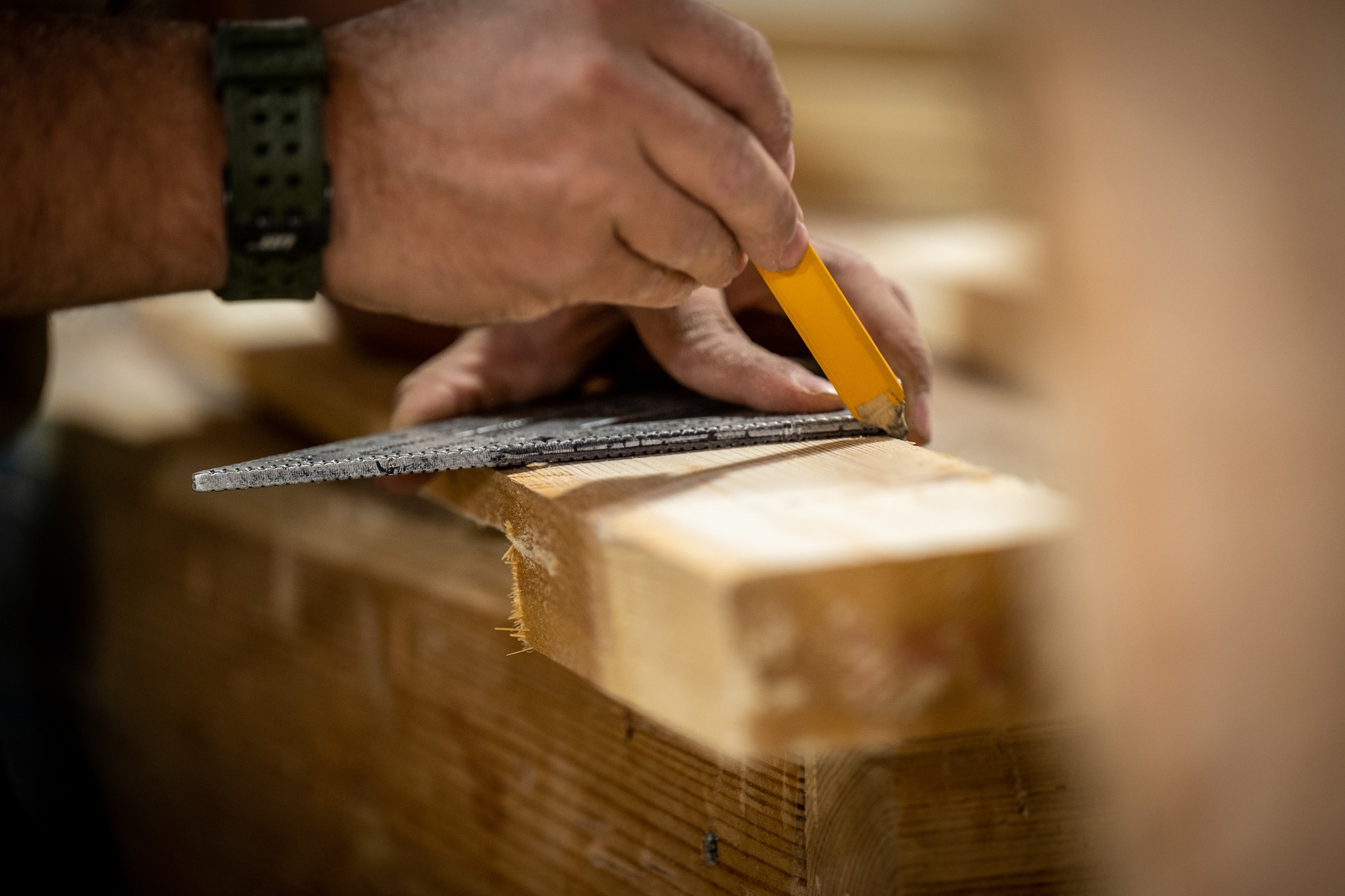 Airman First Class Bryson Doll, 332d Expeditionary Civil Engineer Squadron structural apprentice, marks woodcuts he needs to make for a project at an undisclosed location in Southwest Asia, May 21, 2022. During his deployment, Doll has volunteered 50 hours, before and after work, on various woodworking projects that include bag toss boards, a bench crafted from a shipping palate, a picnic table, a tail fin coin holder, and several other projects. (U.S. Air Force photo by Master Sgt. Christopher Parr)