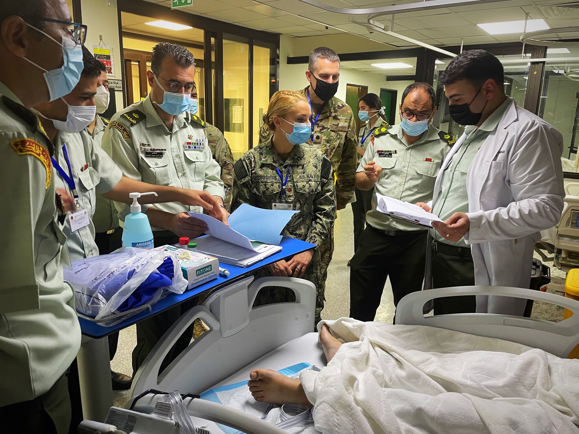 Several Jordanian Royal Medical Service doctors review an intensive care patient’s paperwork alongside Lt. Cmdr. Taylor DesRosiers, Walter Reed Medical Center critical care fellow, and Lt. Col. Erik DeSoucy, Brooke Army Medical Center trauma surgeon and critical care physician, inside the King Hussein Medical Center May 9, 2022 in Amman, Jordan.