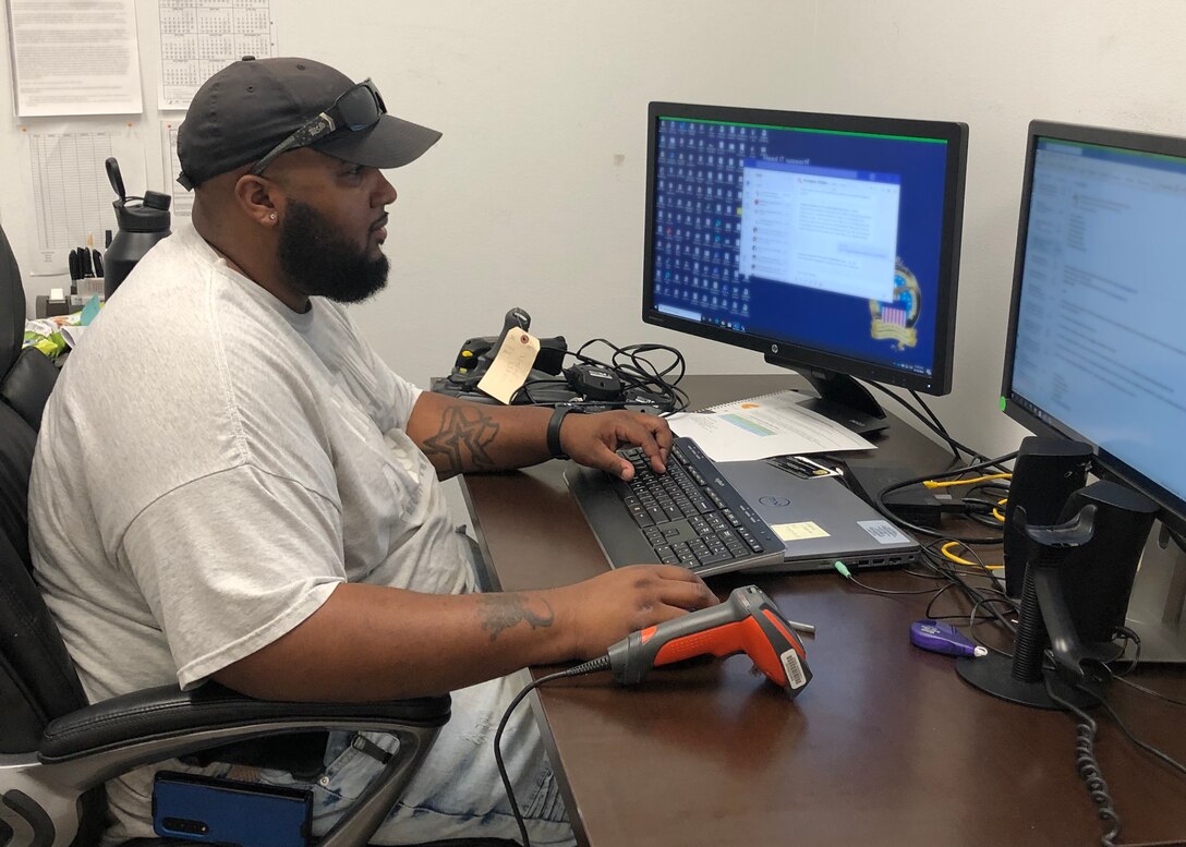 Carlos Chapman Jr Warehouse Supervisor for DLA Disposition Services at Fort Hood, Texas sits at a desk and works on a computer.