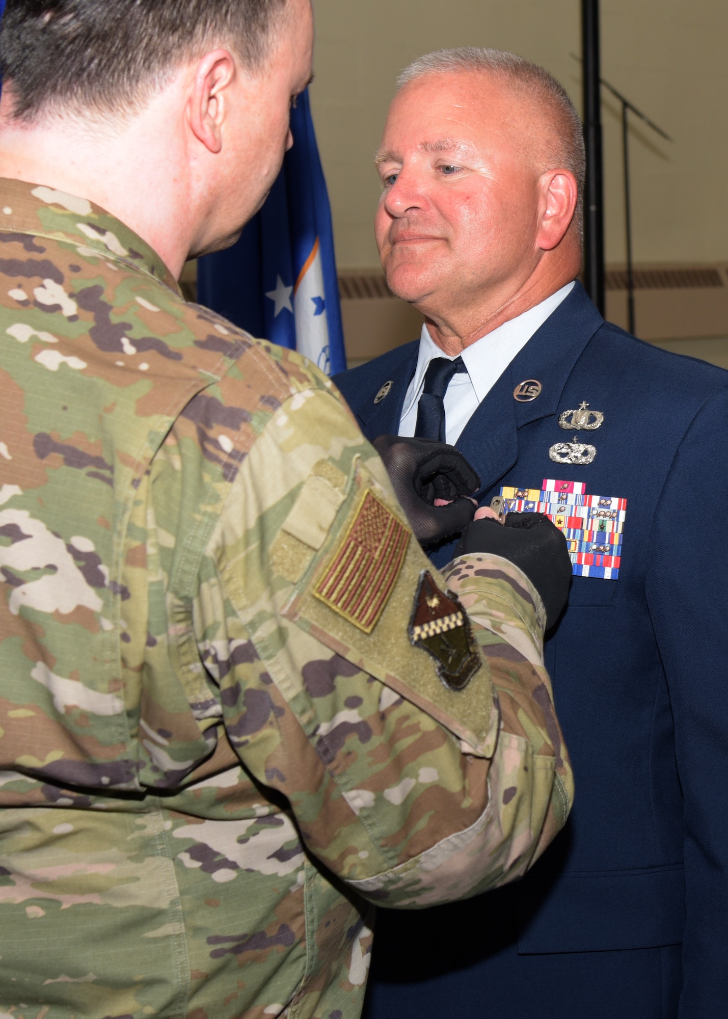 Man in military uniform pins commendation medal on another uniformed military member.