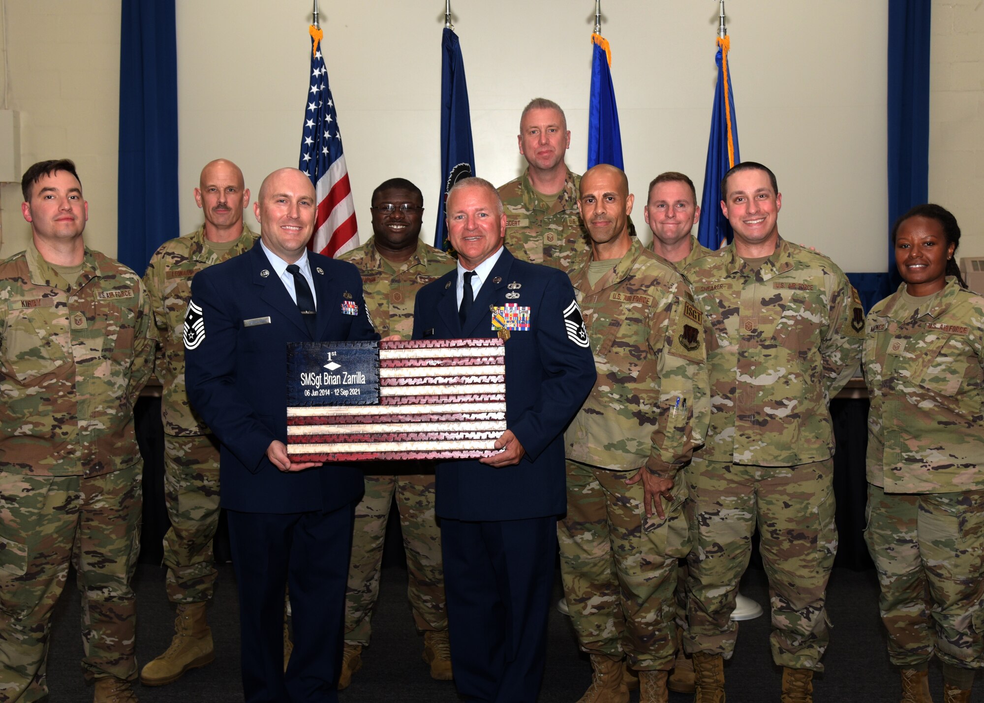 Group of people in military uniform holding an ornamental American Flag.