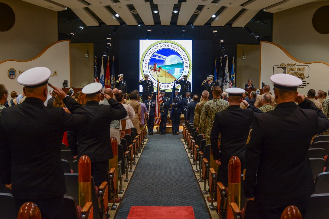 People gather in an auditorium to witness a change of command ceremony.