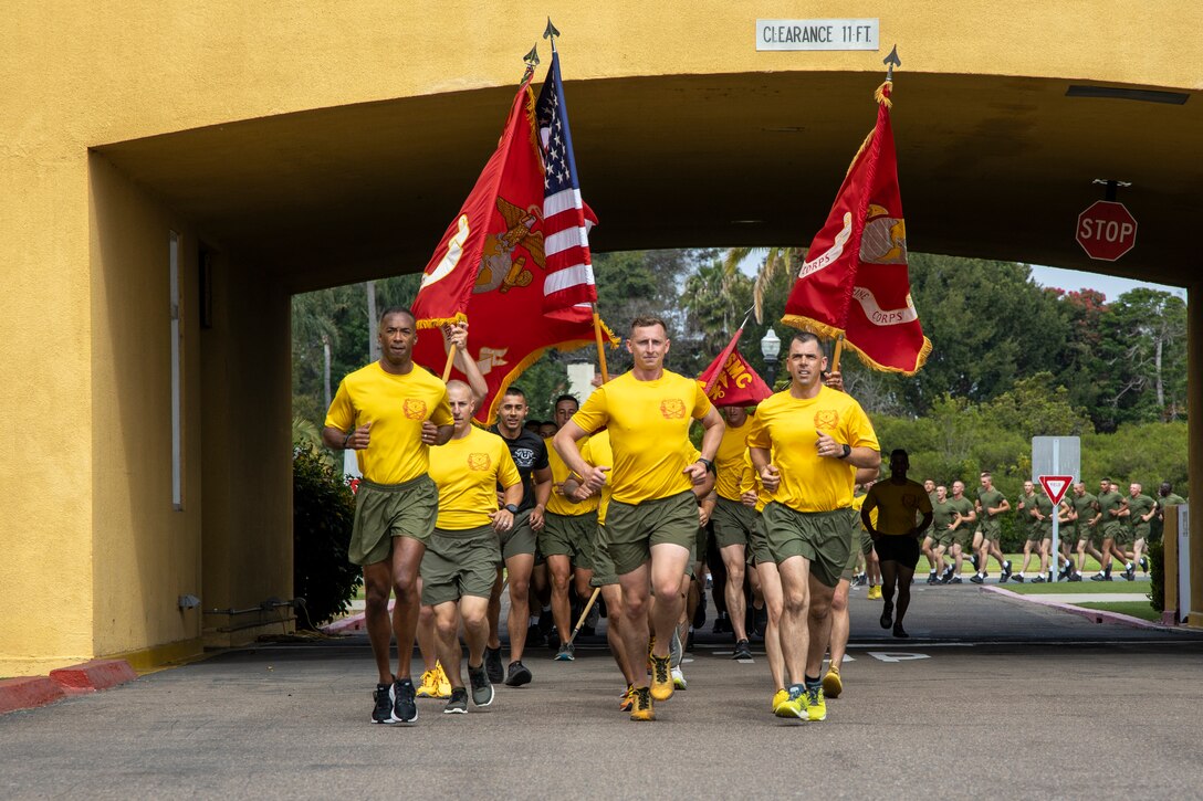 Marines holding flags run in formation.