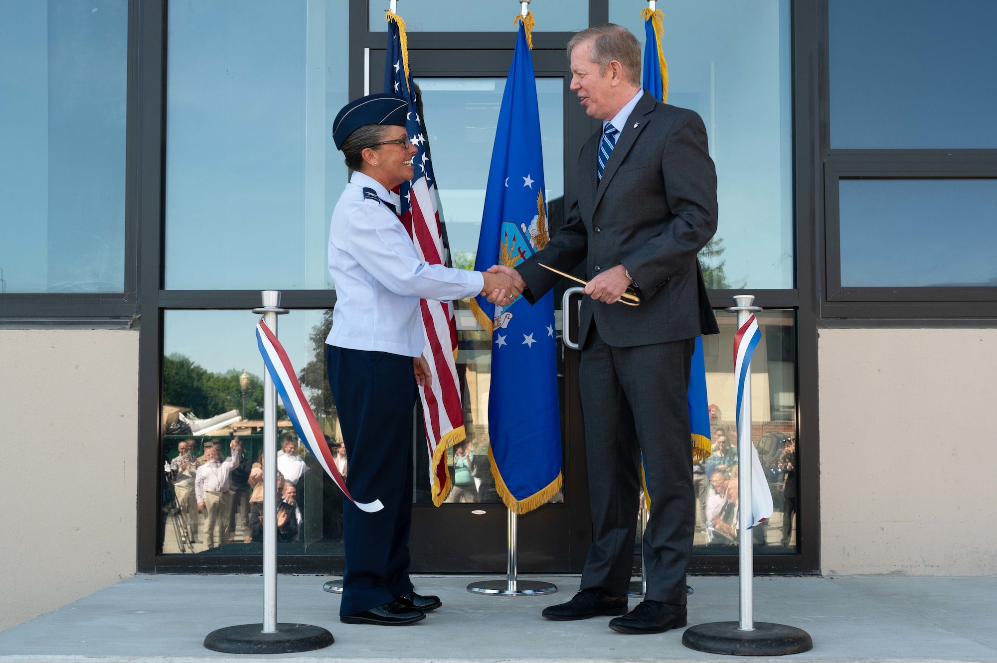 Col. Katrina Stephens, commander, 66th Air Base Group, Hanscom Air Force Base, Mass., and Scott Hardiman, Air Force Nuclear Weapons Center director for Nuclear Command, Control and Communications (NC3) Integration and Air Force program executive officer for NC3, shake hands during a ribbon-cutting ceremony at Hanscom June 6. The ceremony marked the grand opening of building 1102, a 56,000-square-foot facility on base that will provide space for approximately 240 AFNWC personnel, including about 90 unit personnel expected to move over from the MITRE Corp.'s campus in Bedford, Mass. (U.S. Air Force photo by Jerry Saslav)