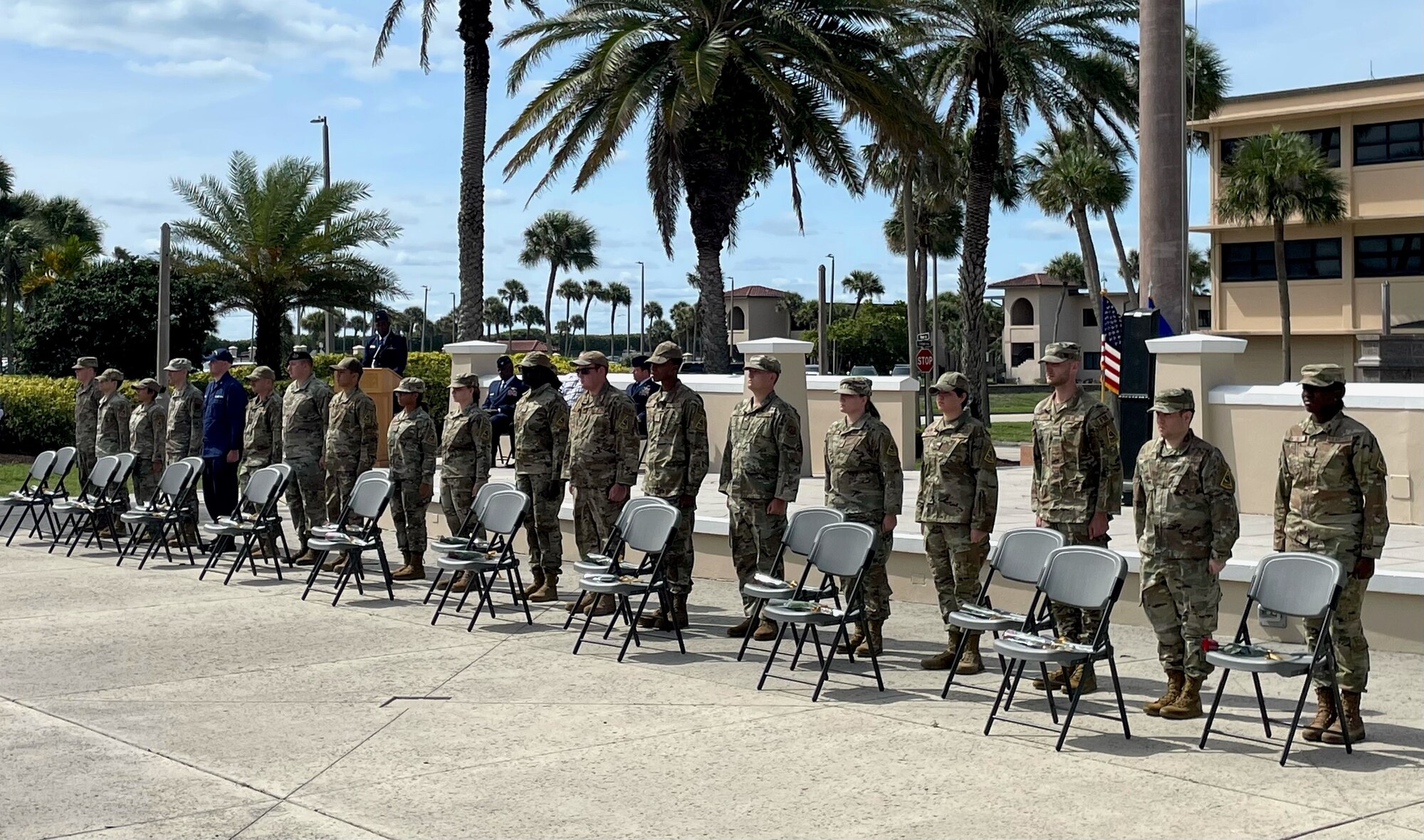 Airmen stand next to 19 chairs with 19 roses and 19 folded flags representing the 19 fallen Airmen during the 26th anniversary Khobar Tower memorial ceremony, June 21, 2021, on Patrick Space Force Base, Florida. On the night of June 25, 1996, a bomb was detonated near the Khobar Tower housing complex in Dhahran, Saudi Arabia, killing 19 Airmen and injuring more than 400 U.S. and international military members and civilians. (U.S. Air Force photo by Staff Sgt. Darius Sostre-Miroir)